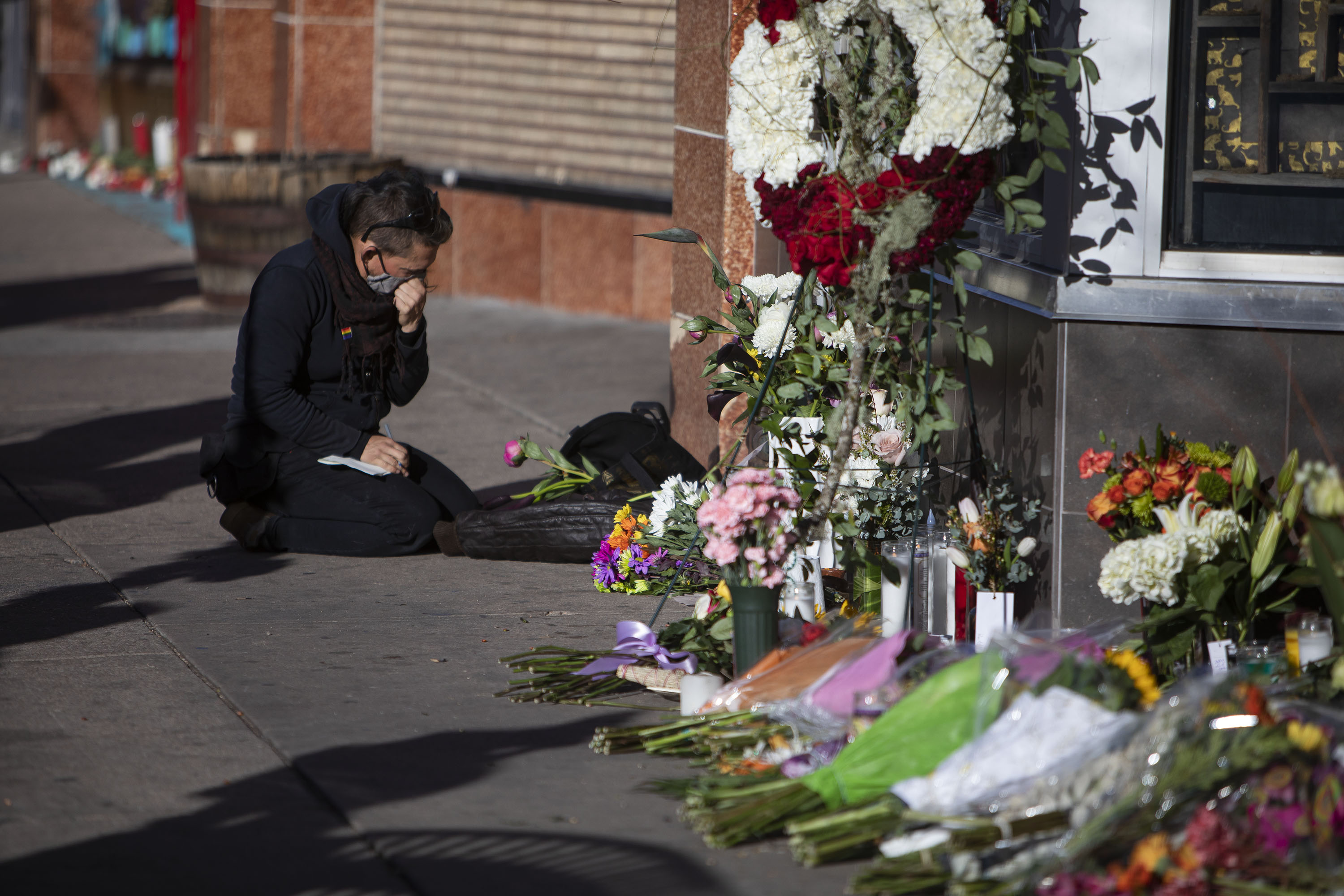 A mourner writes in a notebook at a makeshift memorial for slain tattoo shop owner Alicia Cardenas, who was killed in an overnight shooting spree, as seen on Tuesday, Dec. 28, 2021, in Denver, Colo. (Timothy Hurst/The Gazette) (Timothy Hurst)