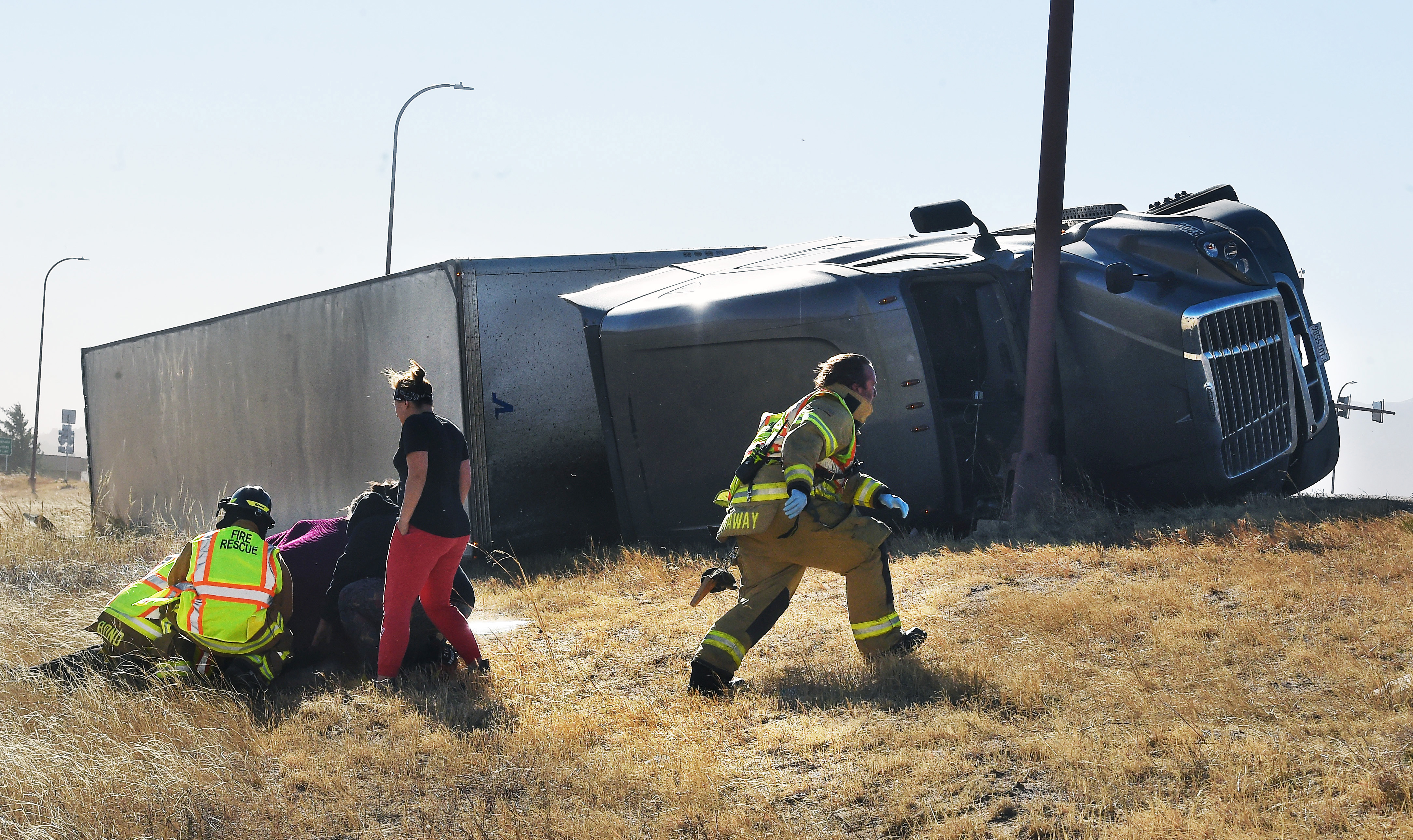 Paramedics tend to an injured person on the onramp of I-25 north of N. Academy Blvd. Over a dozen semi trucks were blown over by high winds in the Pikes Peak region on I-25. (Photo by Jerilee Bennett, The Gazette) (Jerilee Bennett)