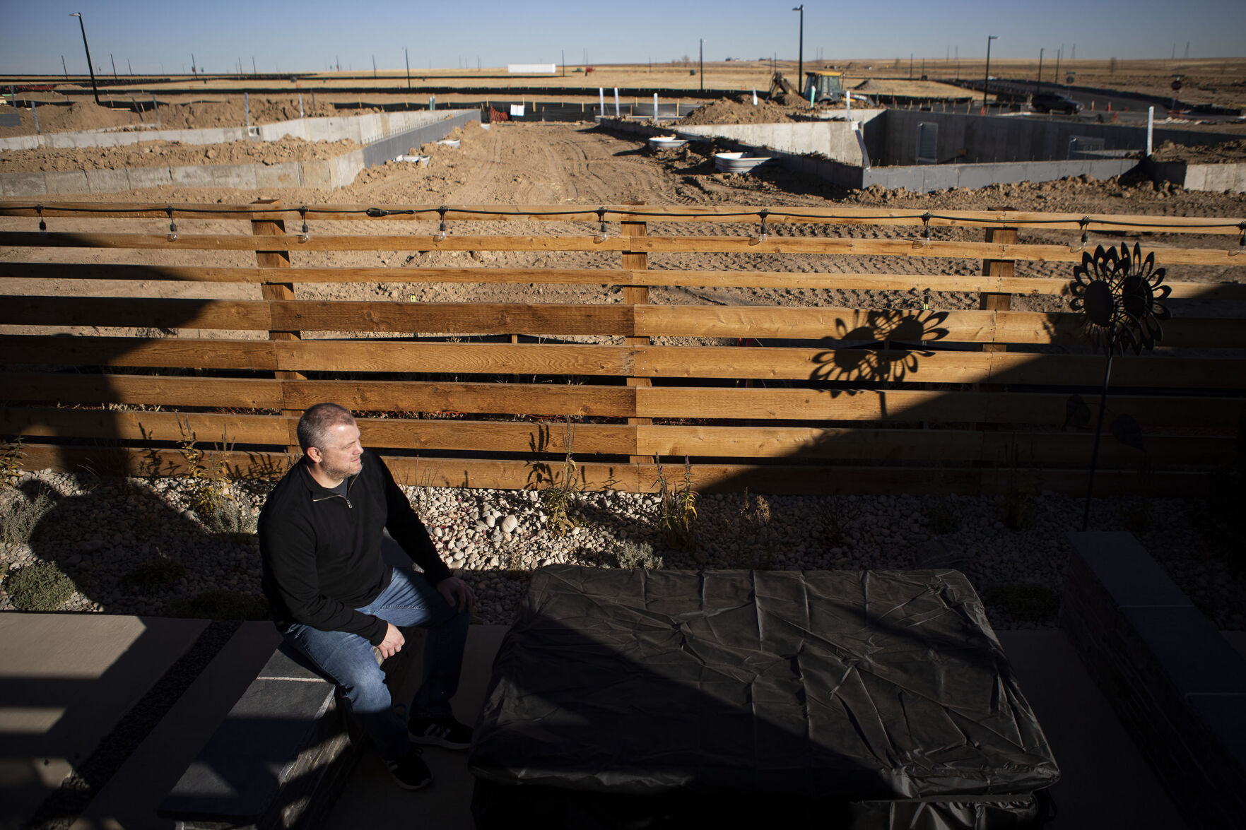 Resident Nick English sits in his backyard while construction on phase two of the Richmond American Homes development goes on in the background during a portrait session on Thursday, Dec. 2, 2021, in the Aurora Highlands Metro District in Aurora, Colo. (Timothy Hurst/The Gazette) (Timothy Hurst, The Gazette)