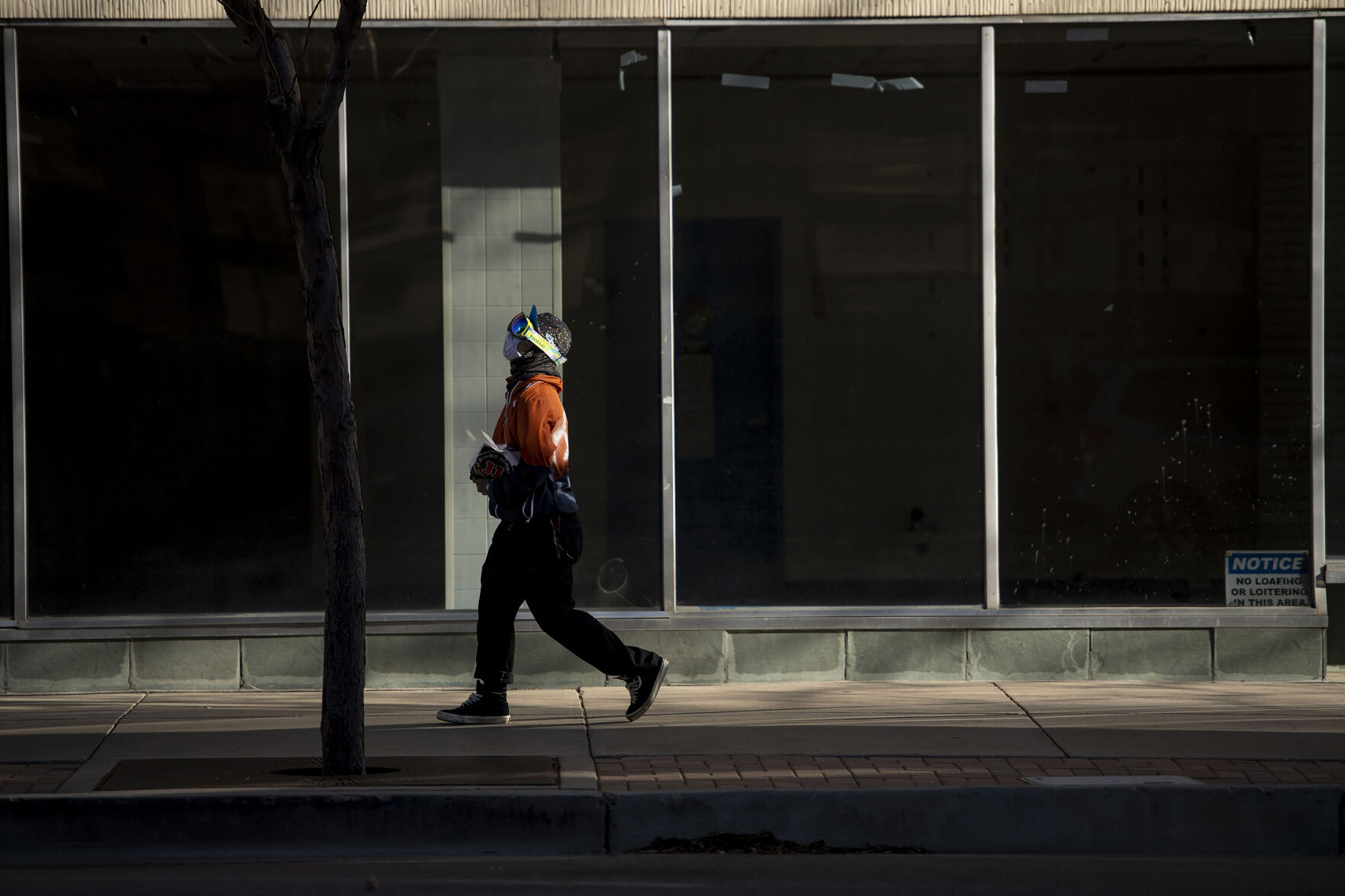 A person wears googles while walking through strong wind gusts, dust and debris in downtown Colorado Springs during a wind storm that swept through El Paso County on Wednesday, Dec. 15, 2021. (Chancey Bush/ The Gazette) (Chancey Bush/ The Gazette)