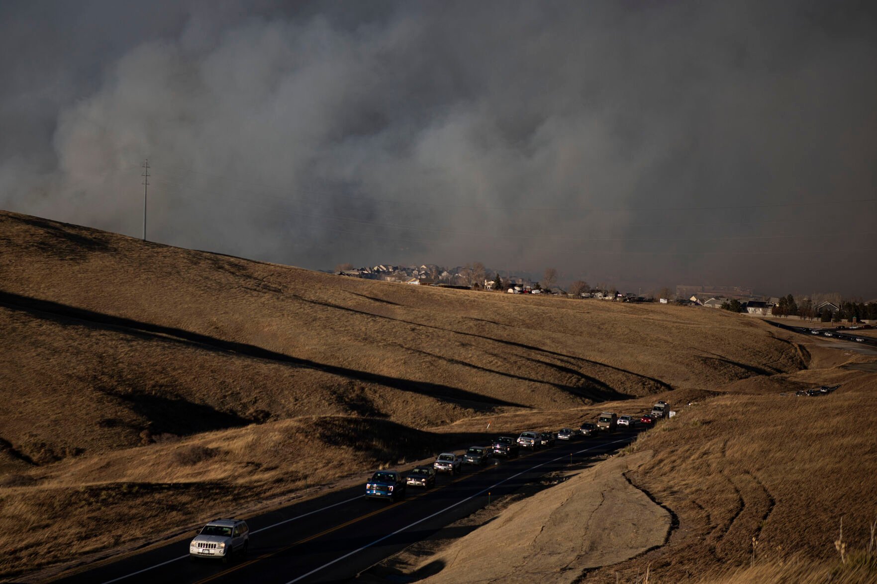 Vehicles evacuate in front of a large grass fire on Thursday, Dec. 30, 2021, in Superior, Colo. (Timothy Hurst/The Gazette) (Timothy Hurst)