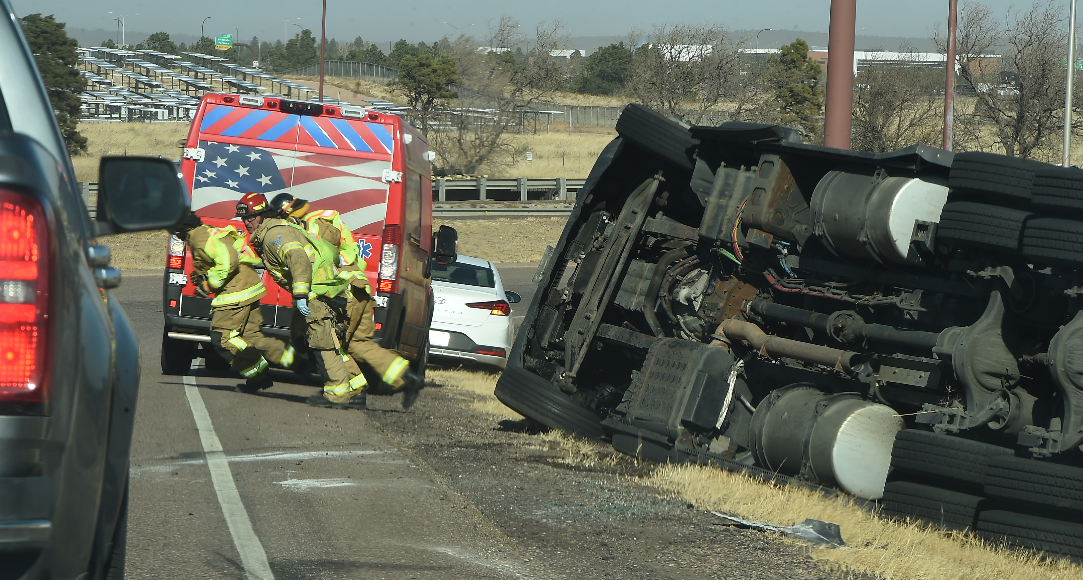 Firefighters head back to their truck in winds that have them walking at almost a 45 degree angle. Over a dozen semi trucks were blown over by high winds in the Pikes Peak region on I-25. (Photo by Jerilee Bennett, The Gazette) (Jerilee Bennett)