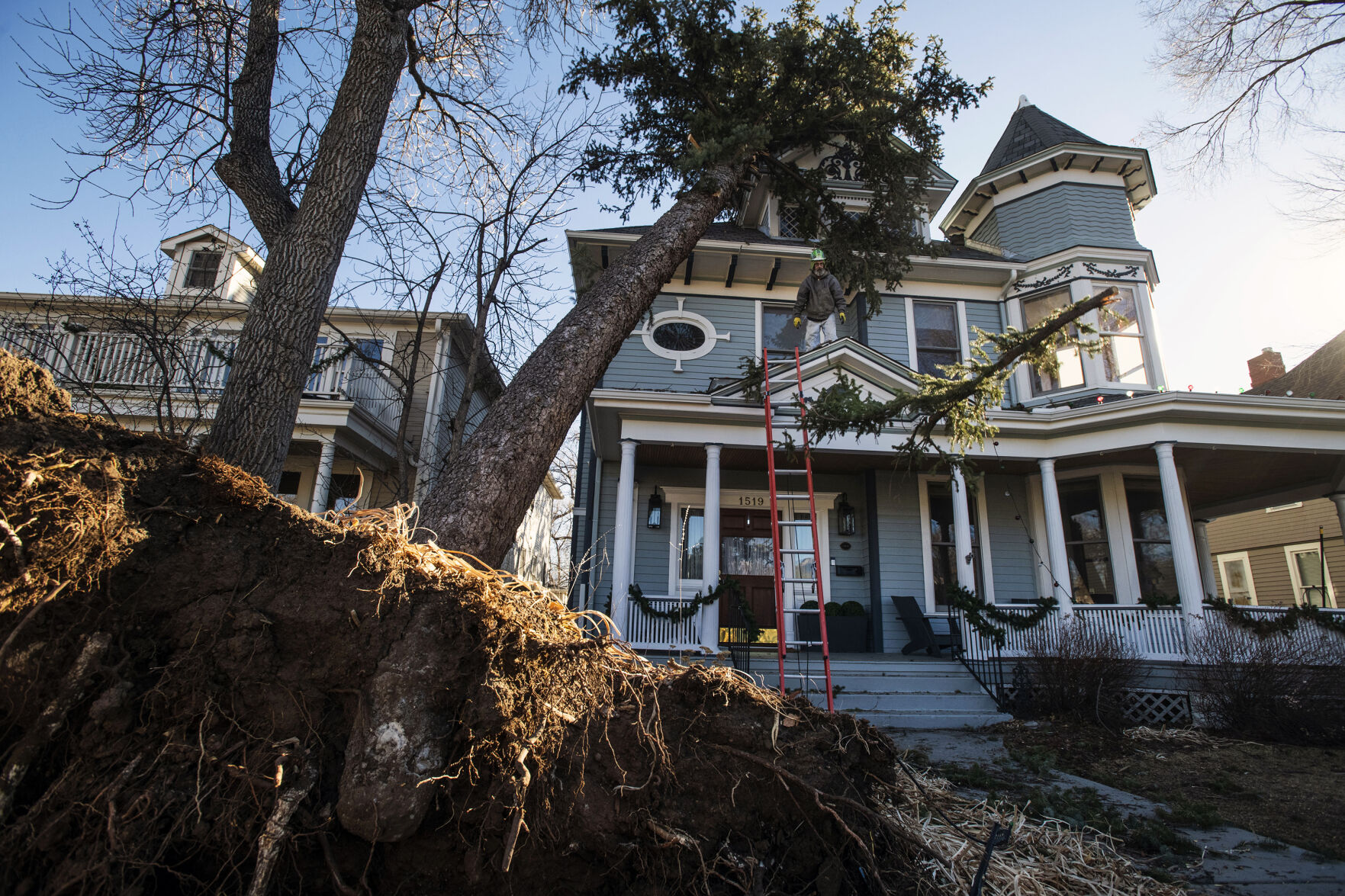 Arborist Tony Bell, co-owner with The Community Tree Service, throws a branch he cut using a pole saw from a tree that fell on a house on Nevada Avenue near Caramillo Street in Colorado Springs on Thursday, Dec. 16, 2021. A wind storm ripped through El Paso County causing major damages to trees, homes, sidewalks and power lines. City crews and tree companies are working to clean up the aftermath of Wednesday’s hurricane-force winds that topped 100 mph in some areas of El Paso County. Colorado Springs Utilities’ crews are working around the clock to fix power lines and restore power to residents still facing outages in areas. (Chancey Bush/ The Gazette) (Chancey Bush/ The Gazette)