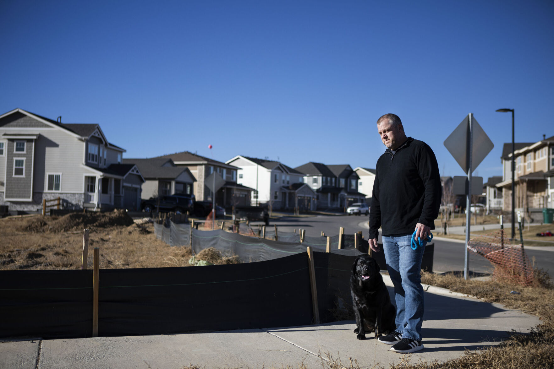 Resident Nick English poses with his dog, Scarlet, at the end of his street still under construction this month in the Aurora Highlands Metro District in Aurora. (Photos by Timothy Hurst, The Gazette)