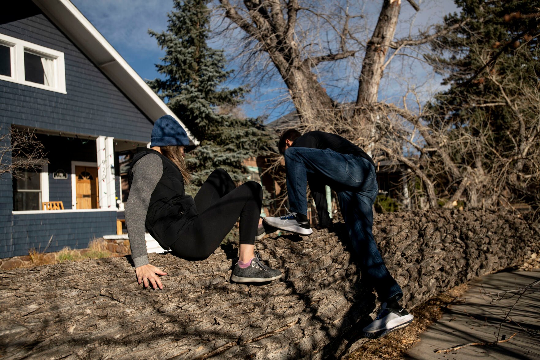 Laura and Jordan Burt climb over a large tree that blew over in front of their home on Boulder Street near Custer Avenue during a wind storm that swept through Colorado Springs on Wednesday, Dec. 15, 2021. (Chancey Bush/ The Gazette) (Chancey Bush/ The Gazette)
