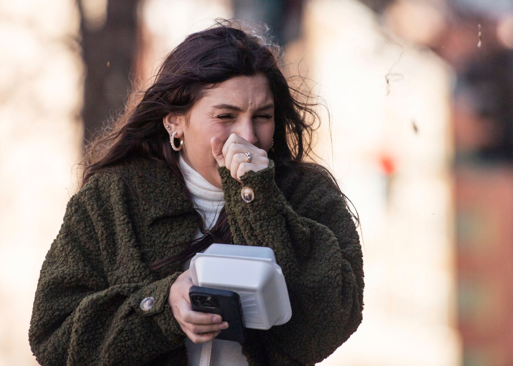 Anna Barber closes her eyes as a strong wind gust blows dust and debris in downtown Colorado Springs during a wind storm that swept through El Paso County on Wednesday, Dec. 15, 2021. (Chancey Bush/ The Gazette) (Chancey Bush/ The Gazette)