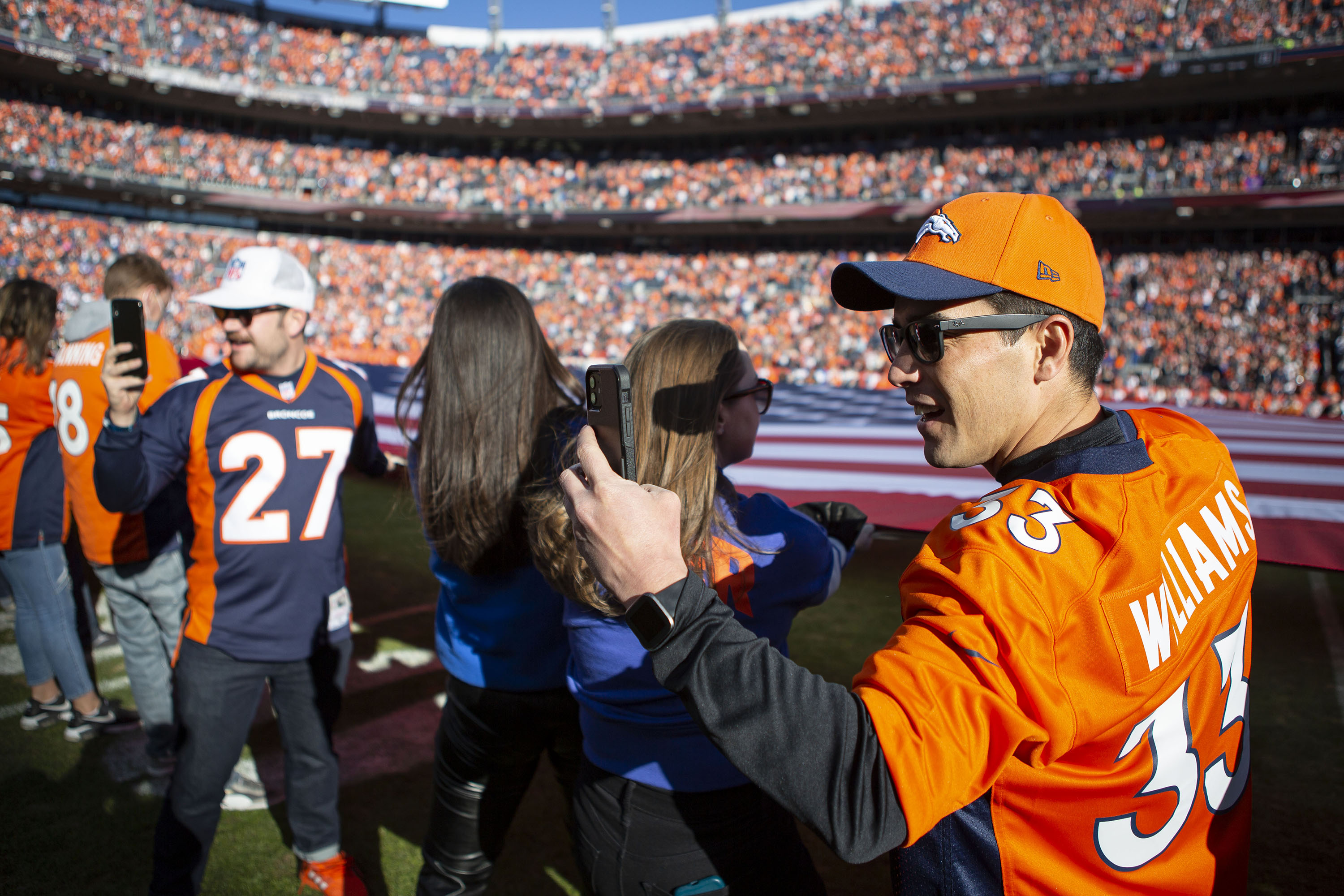 A Denver Broncos fan helping to hold the American flag up takes a selfie before a game against the Cincinnati Bengals on Sunday, Dec. 19, 2021, at Empower Field at Mile High in Denver, Colo. (Timothy Hurst/The Gazette) (TimHursttim.hurst@gazette.comhttps://secure.gravatar.com/avatar/aca82bd62b4ee425c598527cd6faa1b1?d=mm&r=g)