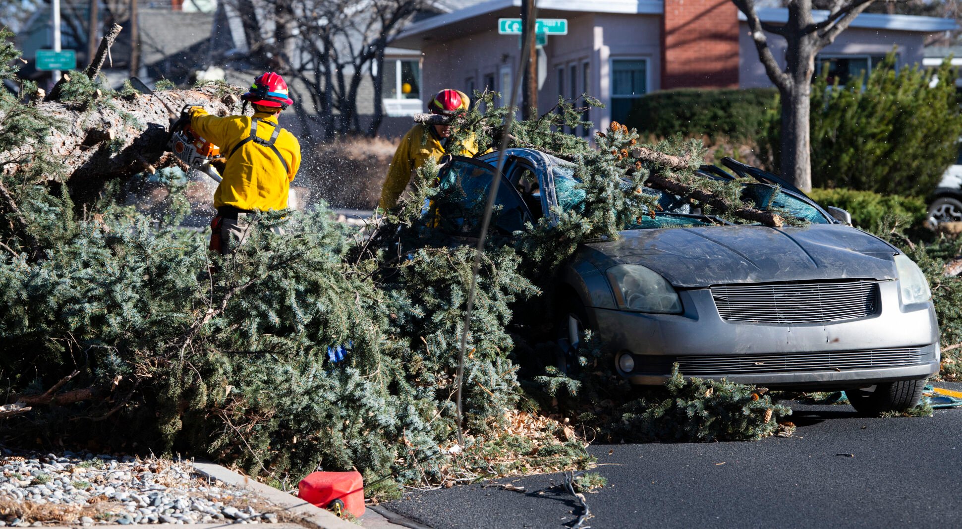 Members of the Colorado Springs Utilities Catamount crew remove a fallen tree the crushed a car driving westbound on Unitah Street in Colorado Springs as wind gusts reached more than 100 mph in the Pikes Peak Region Wednesday, Dec. 15, 2021. The driver and passenger were transported to a local hospital. (The Gazette, Christian Murdock) (Christian Murdock/The Gazette)