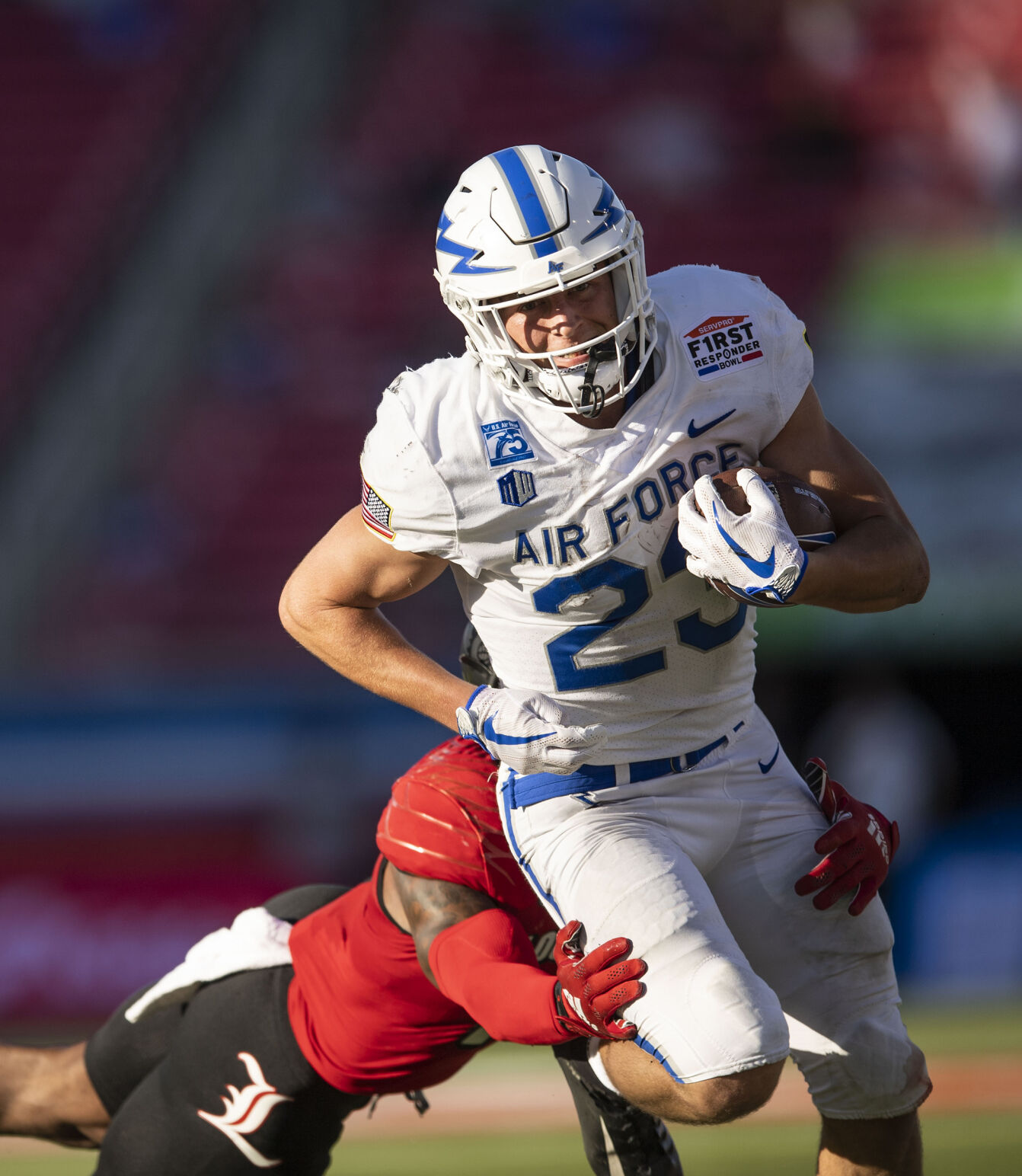 Air Force sophomore Dane Kinamon (23) carries the ball as Louisville senior Qwynnterrio Cole (12) closes in for the tackle during the first half as the Air Force Falcons take on the Louisville Cardinals during the 2021 First Responder Bowl at Gerald J. Ford Stadium on the campus of Southern Methodist University in Dallas, Texas on Tuesday, Dec. 28, 2021. (Chancey Bush/ The Gazette) (Chancey Bush/ The Gazette)