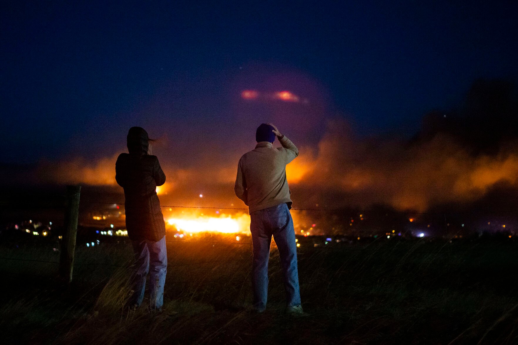 Two people look on while fire moves through a suburban neighborhood on Thursday, Dec. 30, 2021, in Superior, Colo. (Timothy Hurst/The Gazette) (Timothy Hurst)