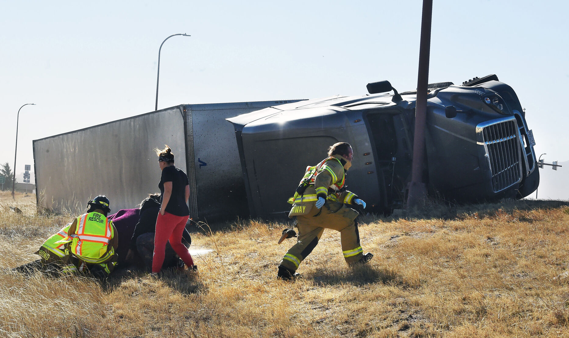 Paramedics tend to an injured person on the onramp of I-25 north of N. Academy Blvd. Over a dozen semi trucks were blown over by high winds in the Pikes Peak region on I-25. (Photo by Jerilee Bennett, The Gazette) (Jerilee Bennett)