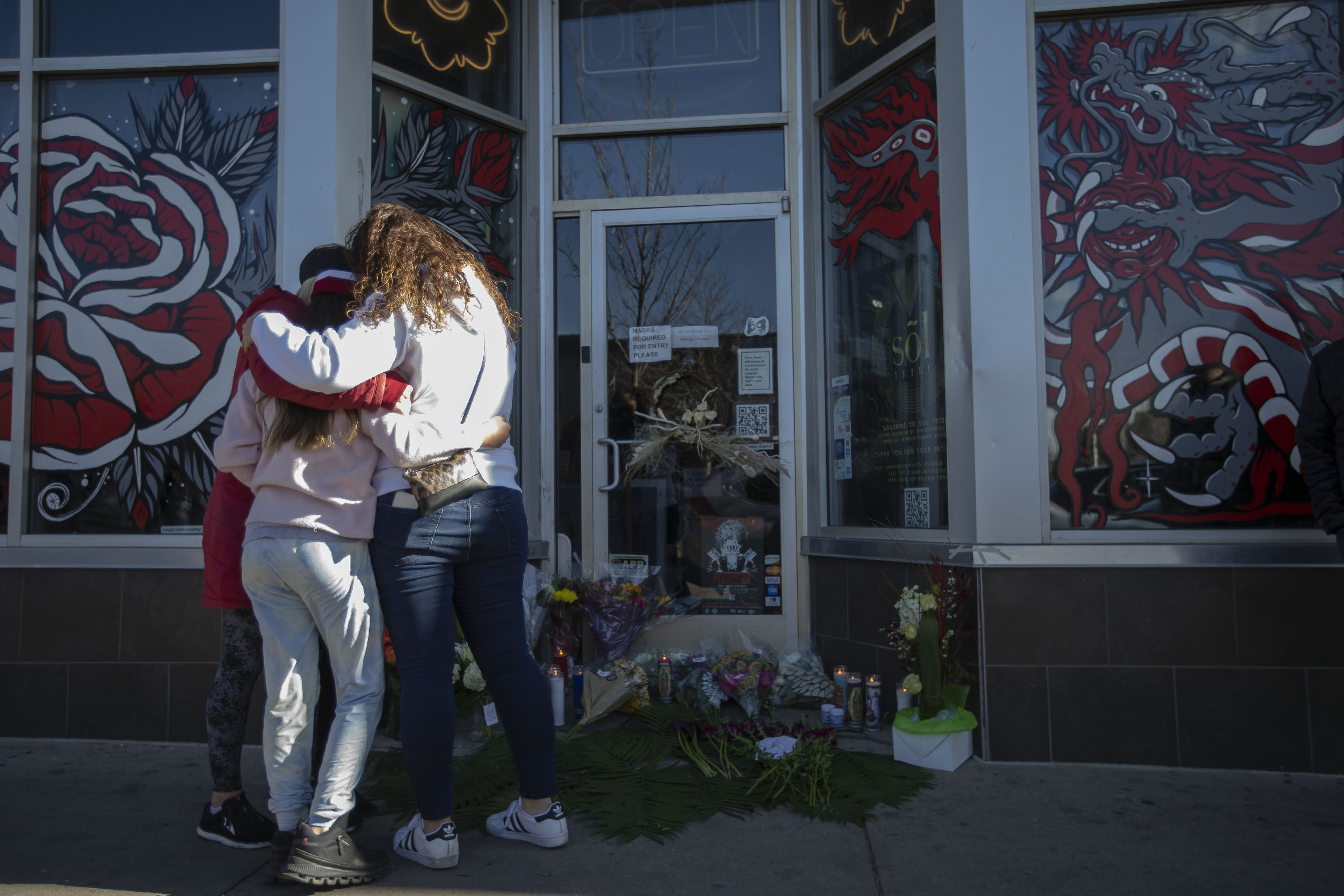 Mourners hug each other in front of Sol Tribe Tattoo & Piercing, the business owned by Alicia Cardenas who was shot and killed in a shooting spree the night before, as seen on Tuesday, Dec. 28, 2021, in Denver, Colo. (Timothy Hurst/The Gazette) (Timothy Hurst)