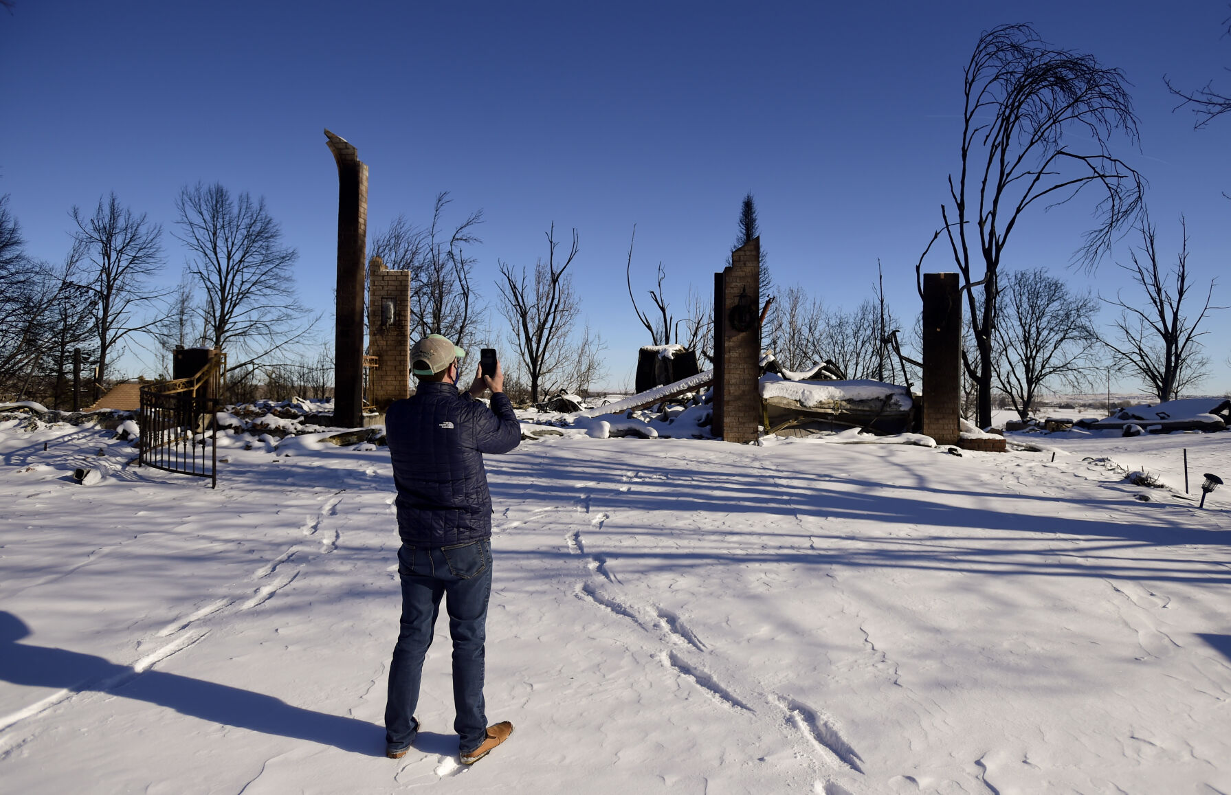 LOUISVILLE, CO - JANUARY 2:U.S. Rep. Jason Crow stops to photograph a home on the 900 Block of St. Andrews Lane during a tour of the Marshall Fire burn area in Louisville on Sunday, Jan. 2, 2022. The current estimate of destroyed structures is 991, while 127 structures are damaged according to Boulder County Sheriff Joe Pelle. (Matthew Jonas/Boulder Daily Camera/Pool) (Matthew Jonas)