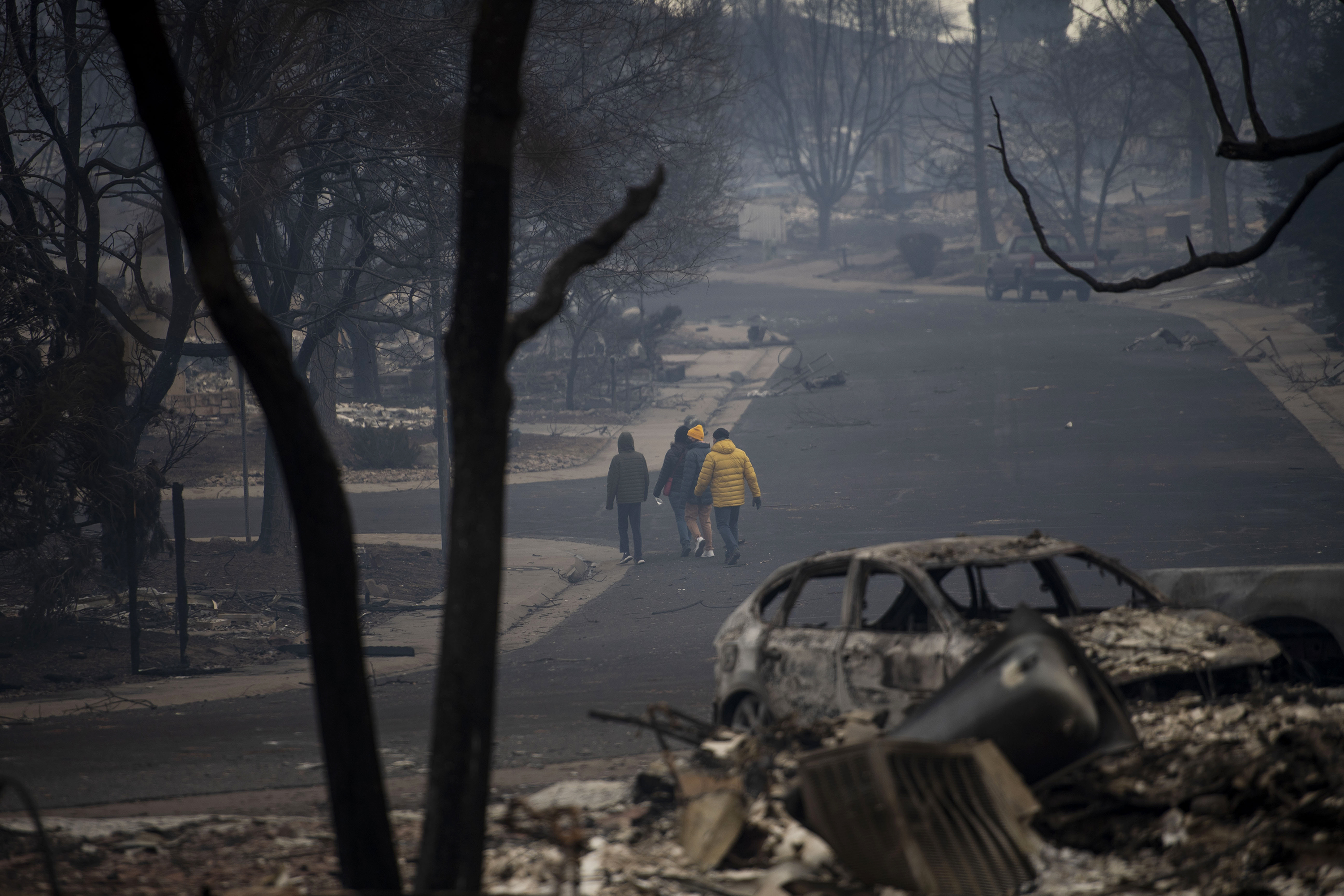 People walk though the destruction across from Davidson Mesa Open Space in Louisville, Colo., on Friday, Dec. 31, 2021. The Marshall fire ripped through Boulder County, fueled by high winds on Thursday, Dec. 30, 2021 and destroying nearly 1,000 homes. Approximately 35,000 people were evacuated in Louisville and Superior.(Chancey Bush/ The Gazette) (Chancey Bush/ The Gazette)