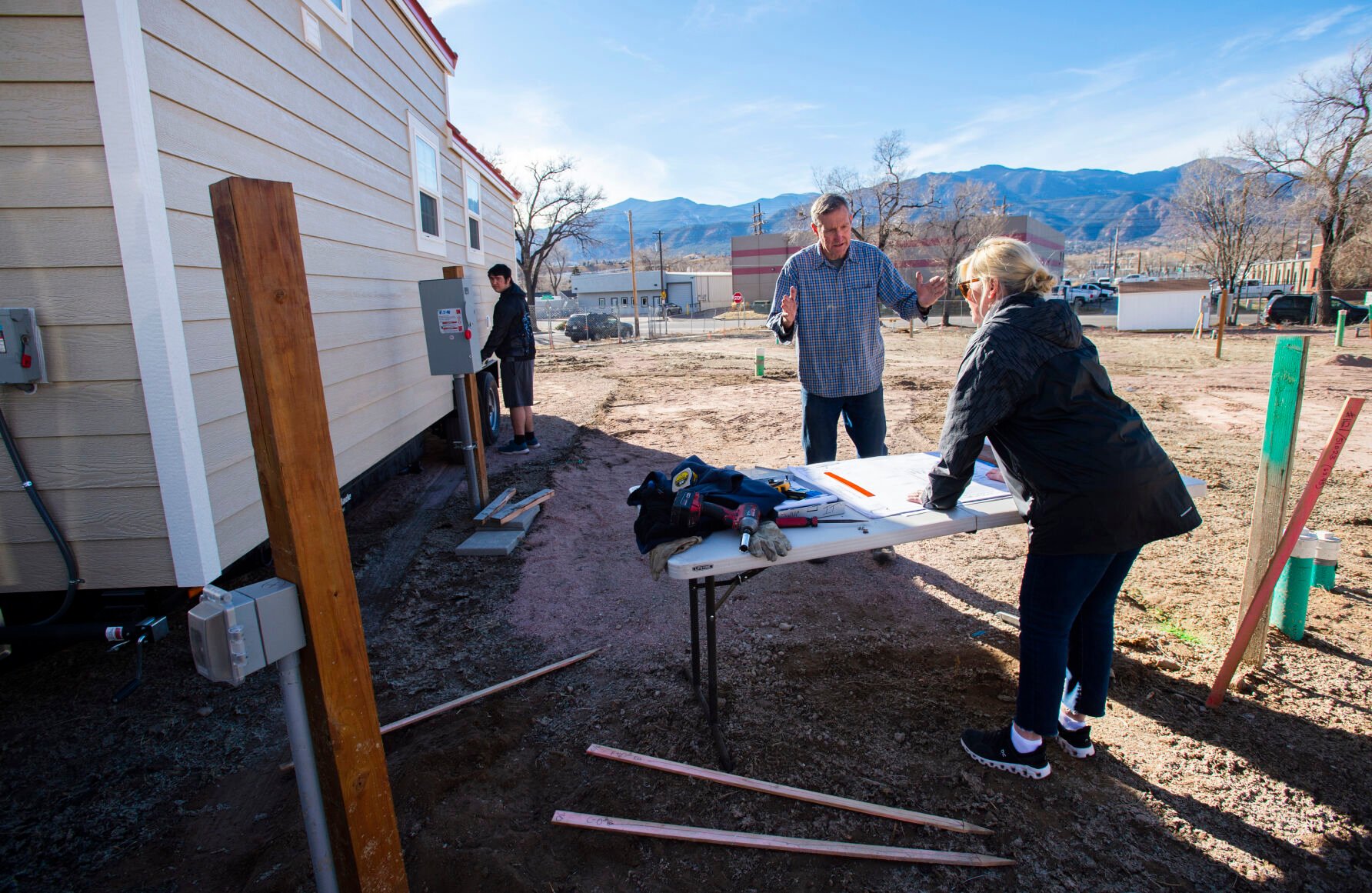 Shelley Jensen, the founder of the nonprofit We Fortify, and Chuck Mingonet look over the layout designs Tuesday, Jan. 11, 2022, as the first five tiny homes are put into place at the Working Fusion development in the Mill Street neighborhood. The development, which will include 18 tiny homes when finished, will shelter former homeless from 18 to 25. (The Gazette, Christian Murdock) (Christian Murdock/The Gazette)