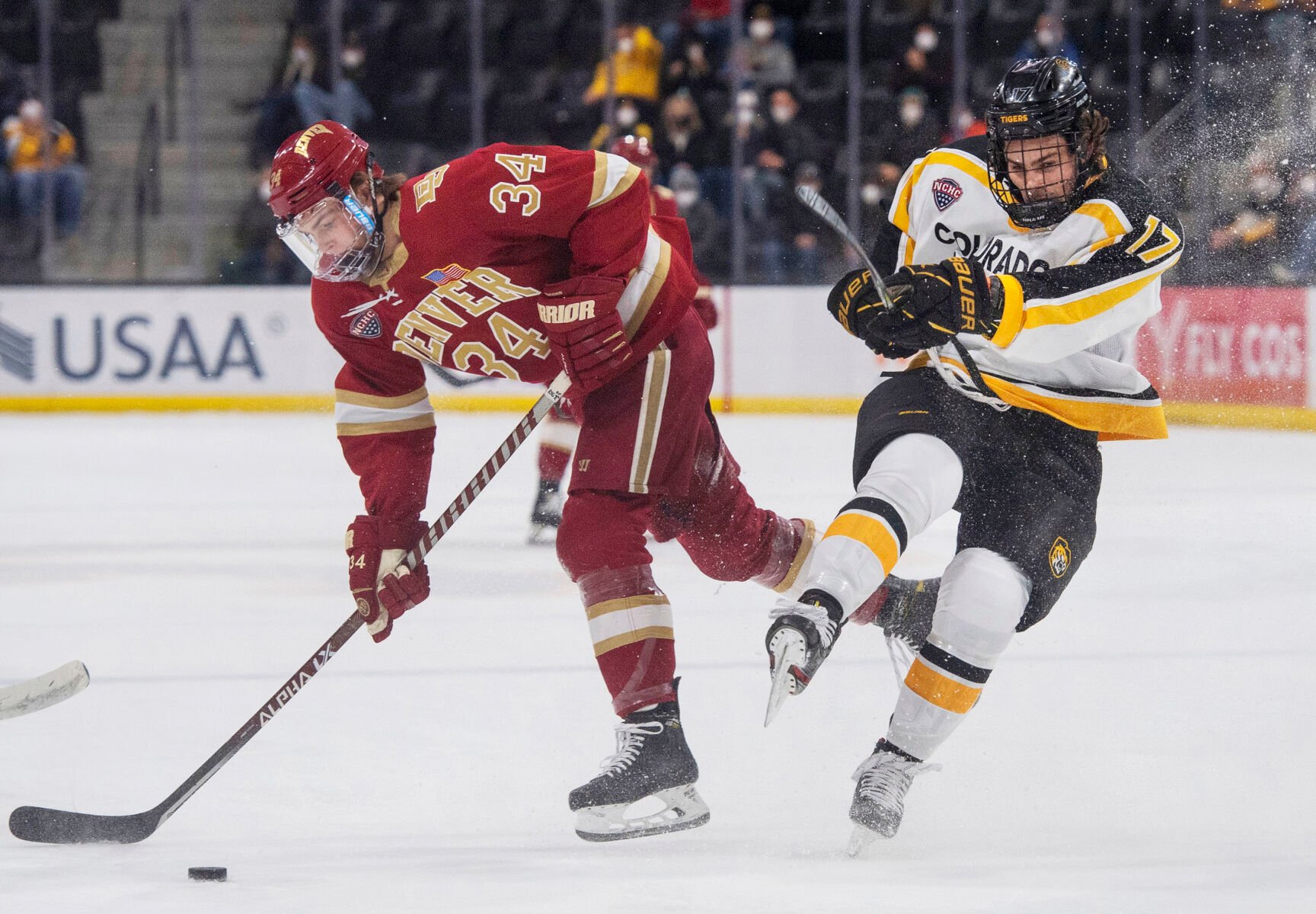 Colorado College sophomore forward Tyler Coffey (17) gets tripped up by Denver freshman forward Carter Mazur (34) as the CC Tigers take on the University of Denver Pioneers at Ed Robson Arena on the campus of Colorado College in Colorado Springs Colo., on Saturday, Jan. 22, 2022. The Tigers lost the game against the Pioneers by a score of 4 to 0.(Chancey Bush /The Gazette) (Chancey Bush/ The Gazette)