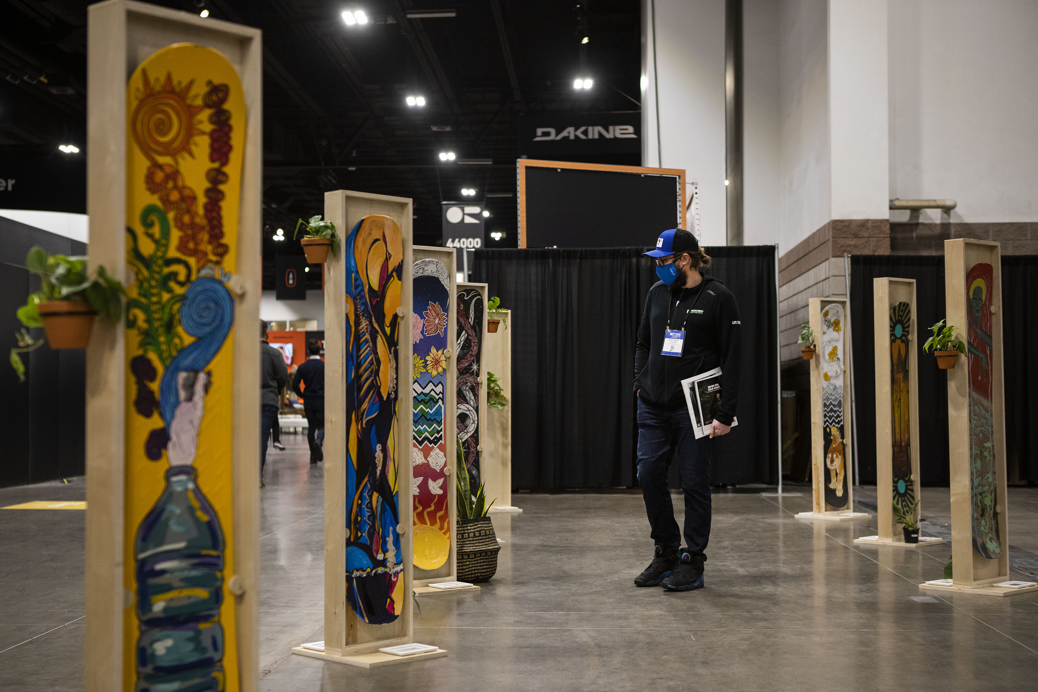 Life Time Events regional sales manager Mickey Martin checks out a series of snowboards shaped and painted by artists on display during the second day of the Outdoor Retailer Snow Show at the Colorado Convention Center on Thursday, Jan. 27, 2022, in Denver, Colo. (Timothy Hurst/The Gazette) (Timothy Hurst/The Denver Gazette)