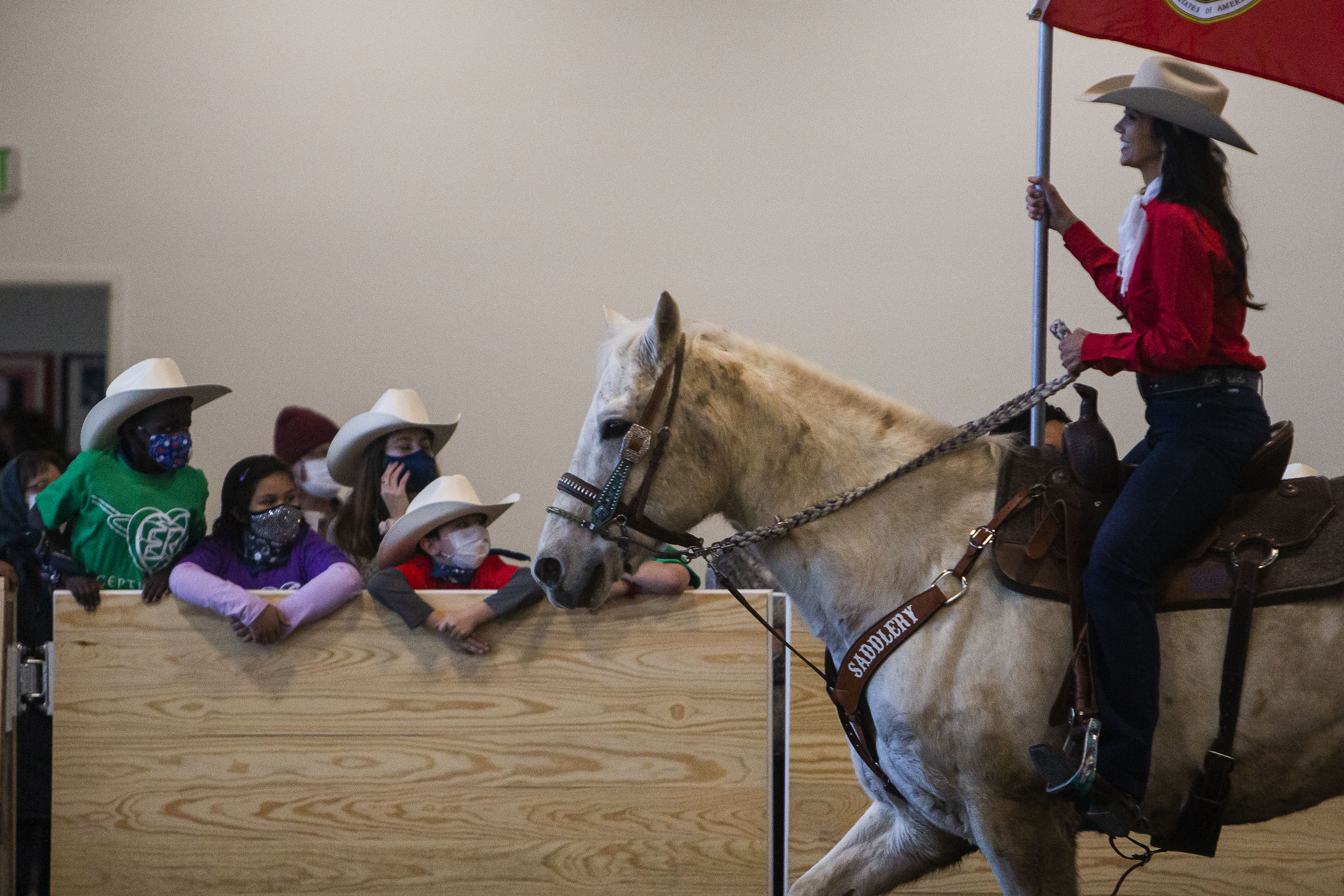 Children lean over the wall as the Colorado Stars & Stripes, Co. presents a series of flags during the Exceptional Rodeo in the Temple Grandin Equine Center on Thursday, Jan. 20, 2022, at the CSU Spur Campus in Denver, Colo. (Timothy Hurst/The Gazette) (Timothy Hurst)