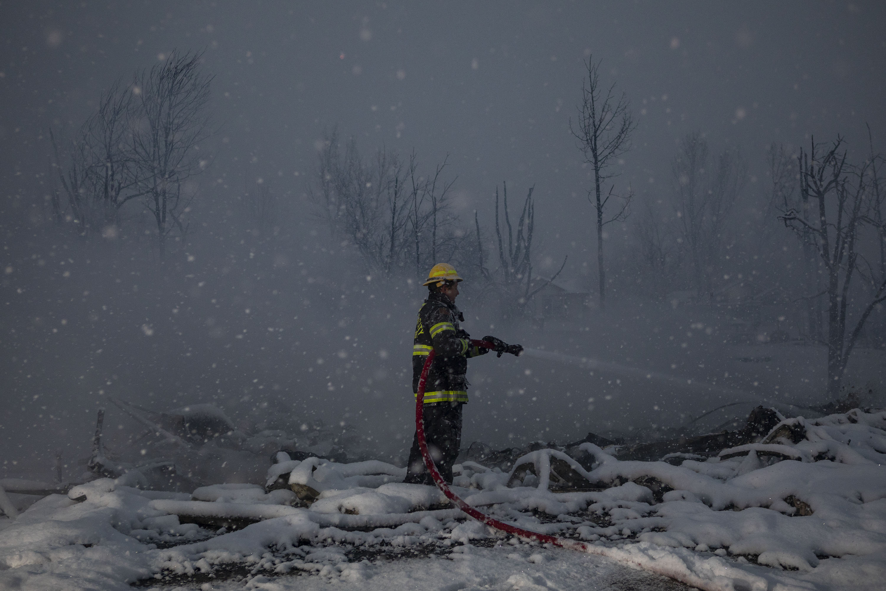 A Central City Fire Department firefighter sprays down the hot debris that’s accumulated in the basement of a home that burned down on the 2000 block of Andrew Drive on Friday, Dec. 31, 2021, in Superior, Colo. (Timothy Hurst/The Gazette) (Timothy Hurst)