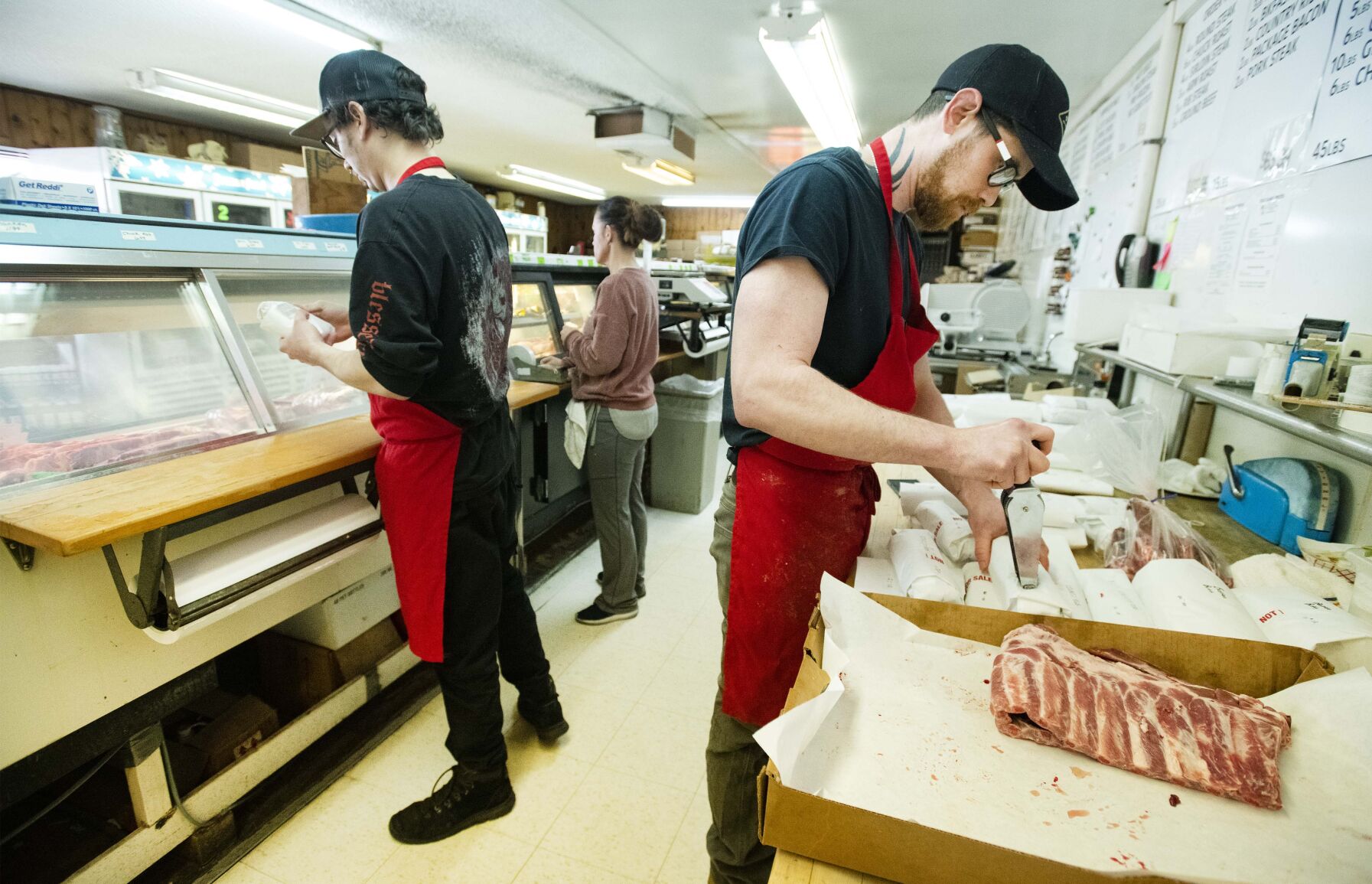 Mike Wright, right, Austin McKay, left, and Lacie Clark fill orders behind the counter Tuesday, Jan. 25, 2022, at Andy’s Meat Market in Colorado Springs. The local meat market will close after 70 years on Feb. 26. (The Gazette, Christian Murdock) (Christian Murdock/The Gazette)