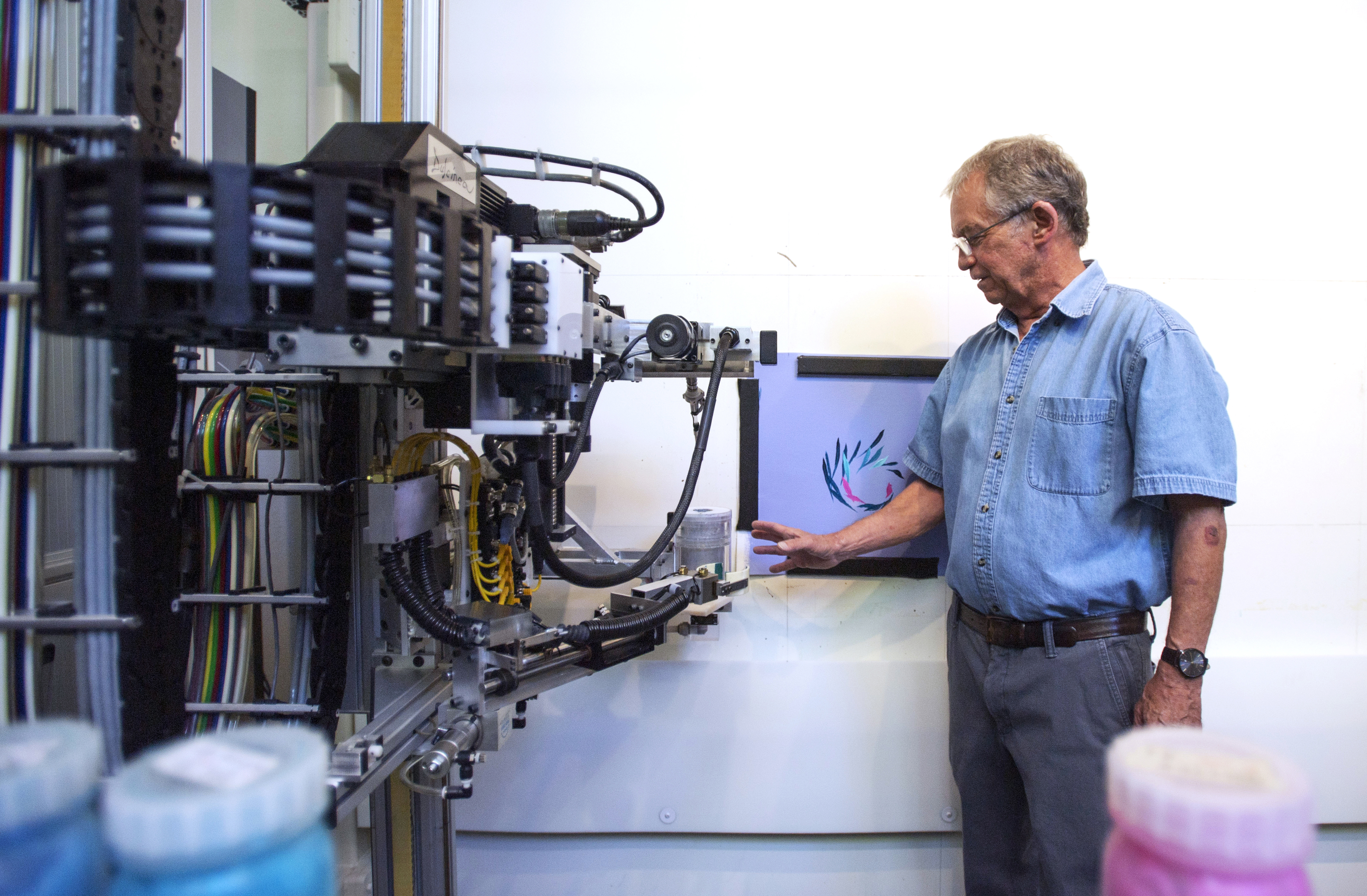Artist Paul Kirby stands next to Dulcinea, a robot he invented that can paint beyond what the human hand is capable of, at his studio in Loveland. It’s part of Kirby’s journey to fuse art and science. (Chancey Bush, The Gazette)