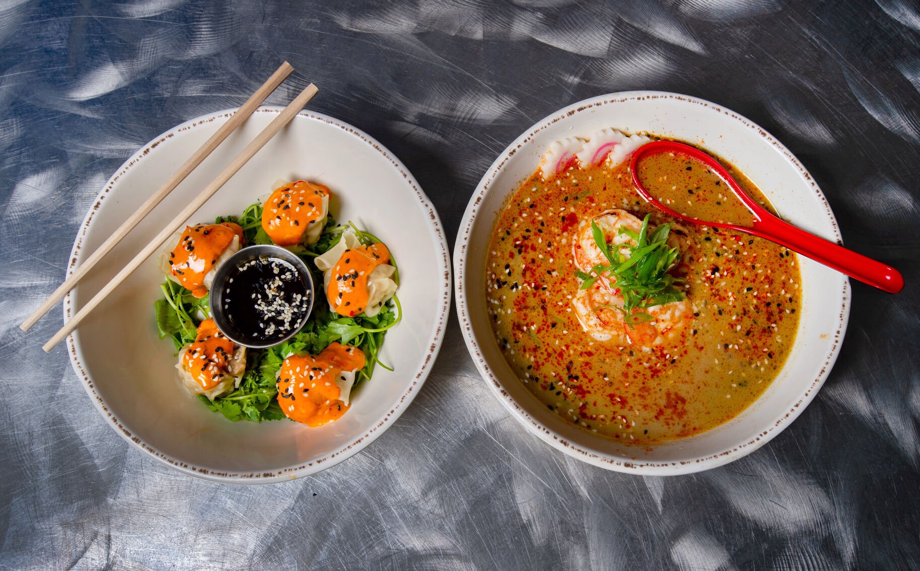 Lemongrass and yuzu pork shumai with gochujang cream and white soy and yuzu dipping sauce, left, and white soy and rice wine marinated BBQ shrimp with miso broth and sweet and sour tare and fish cake at Rooster’s House of Ramen in Colorado Springs. (Christian Murdock, The Gazette)