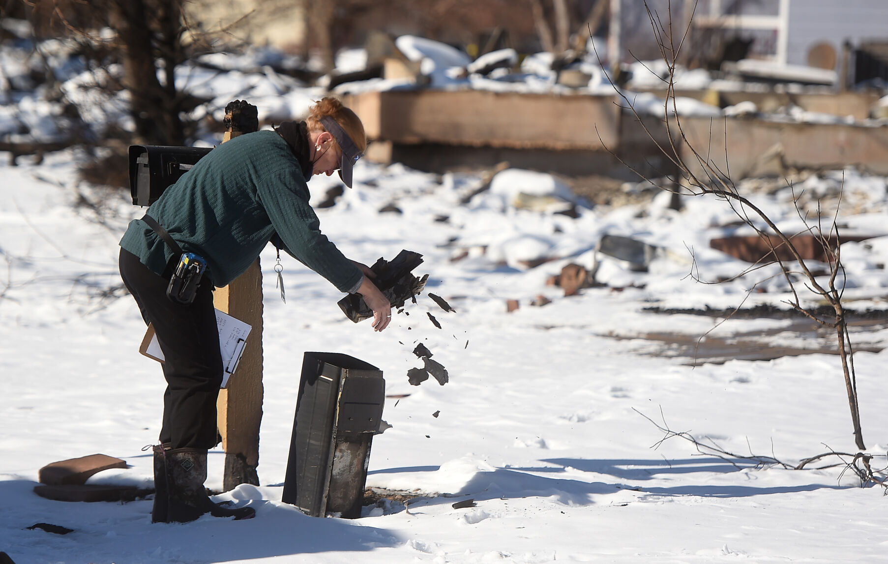 The mail from a burned home in Superior disintegrates in the hands of USPS carrier Courtney Brooks. Brooks was running her regular route in Superior and keeping notes of which homes were still there and which were gone on Sunday, Jan. 2, 2022. Brooks and other volunteering postal workers from around the state wanted to give the people in the affected area of the Marshall Fire a feeling of normalcy by delivering their mail and also asking any questions they might have about mail delivery. (Photo by Jerilee Bennett, The Gazette) (Jerilee Bennett)