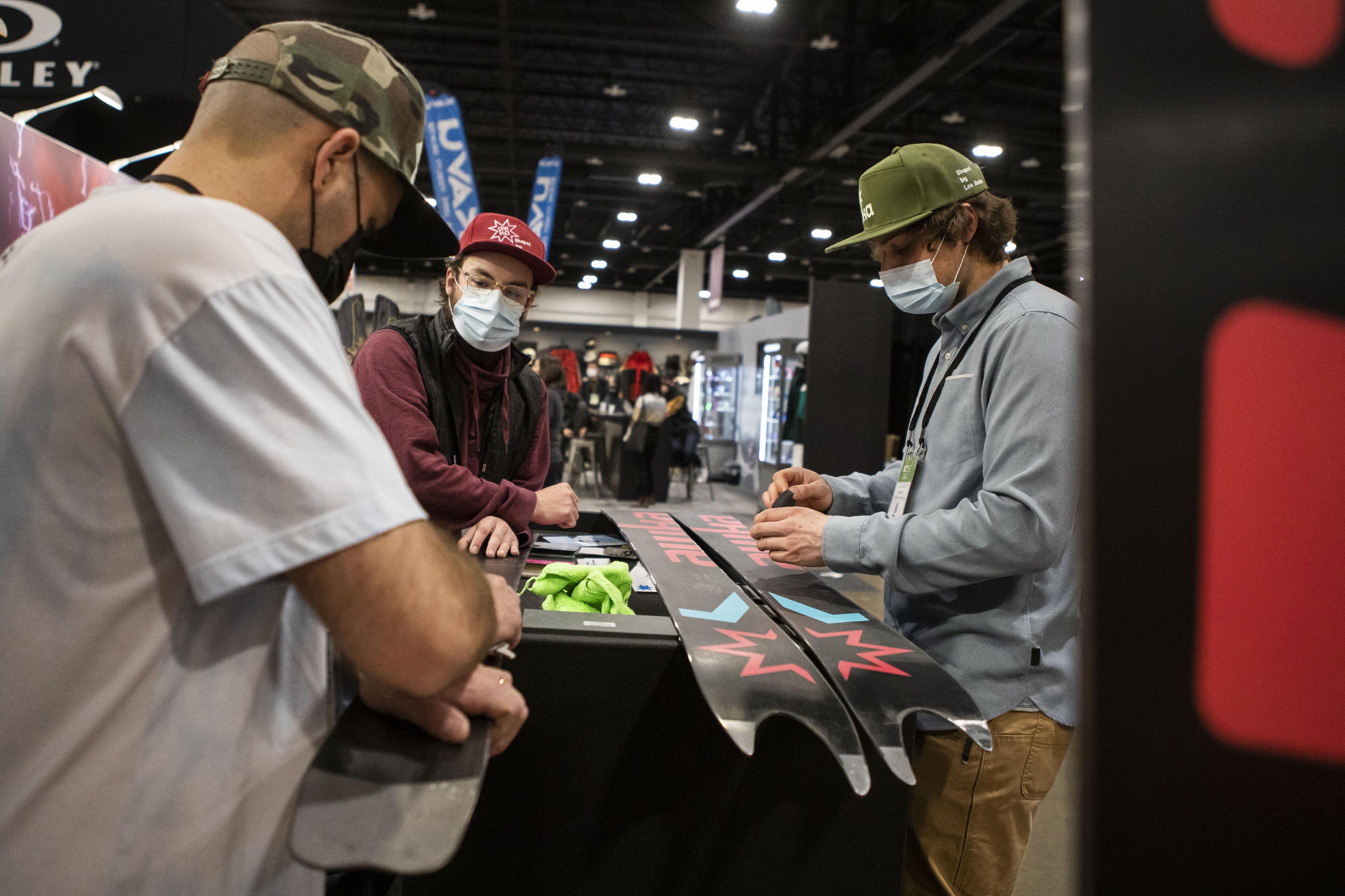 Wyatt Daigle, right, Nathan Nordell, center, and Juan Ignacio Tejeda, all with Chilean company Awka Skis, clean and wax skis with a swallowtail design on the back of the skis during the second day of the Outdoor Retailer Snow Show at the Colorado Convention Center on Thursday, Jan. 27, 2022, in Denver, Colo. (Timothy Hurst/The Gazette) (Timothy Hurst/The Denver Gazette)