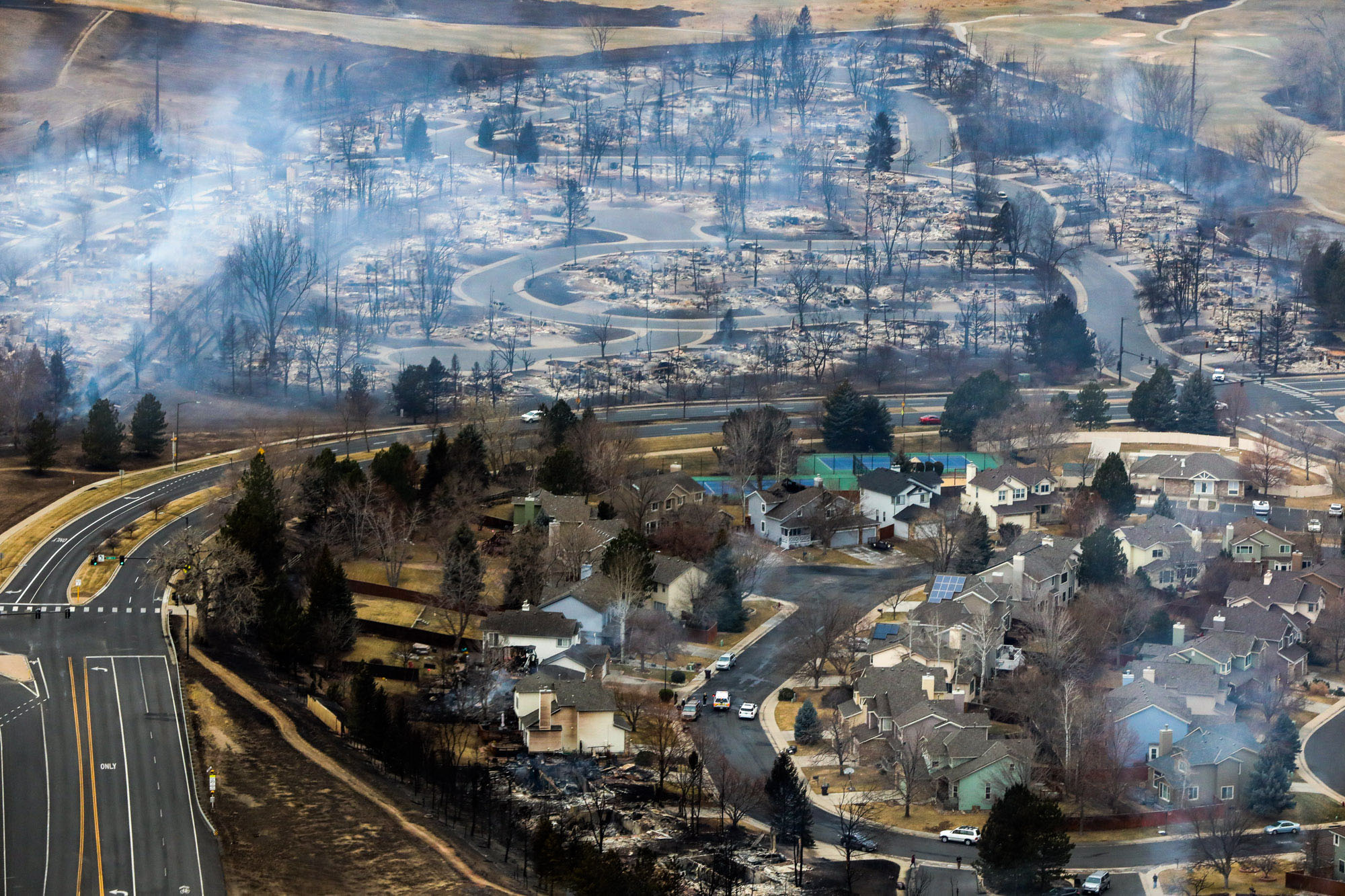 Aboard a Colorado National Guard helicopter, Gov. Jared Polis on Friday, Dec. 31, 2021, gets a flyover tour of Boulder County neighborhoods destroyed by wildfires the previous day. He was accompanied by Brig. Gen. Laura Clellan, Adjutant General of Colorado, and Boulder County Sheriff Joe Pelle. Colorado U.S. Sen. Michael Bennet and Rep. Joe Neguse also toured the area in a separate helicopter. (Hart Van Denburg/CPR News)