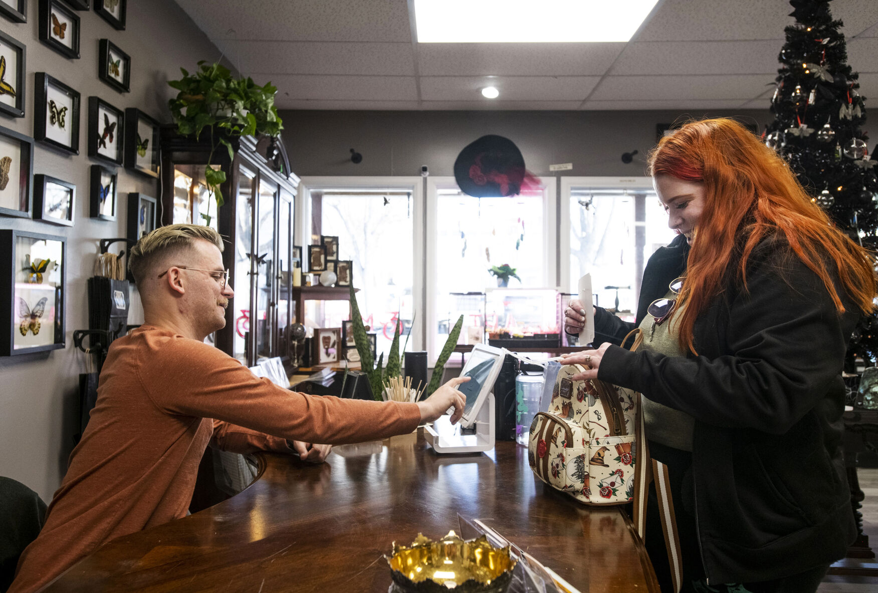 Cronkrings up customer Candice German at his store in downtown Colorado Springs. (Chancey Bush, The Gazette)