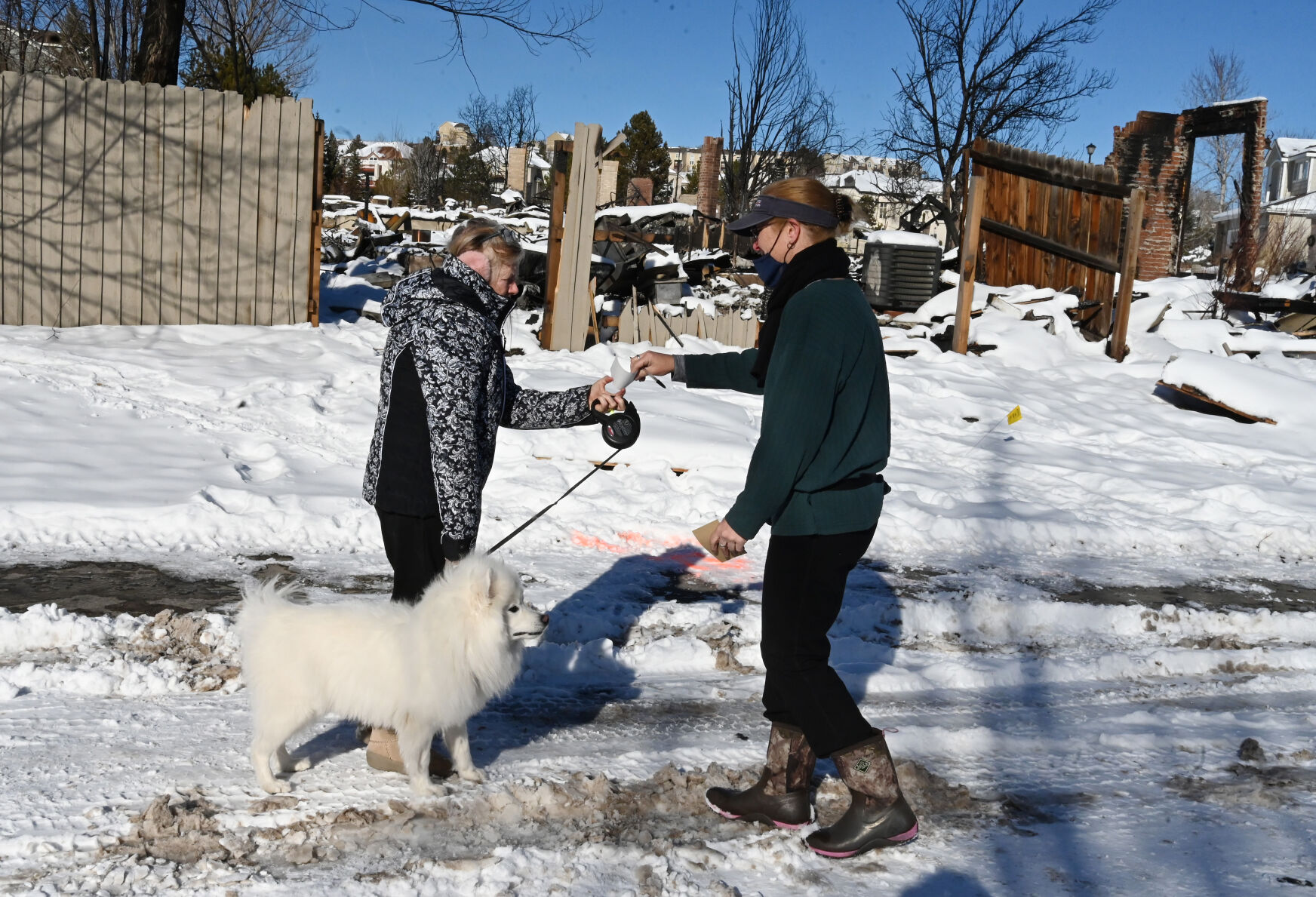 USPS carrier Courtney Brooks hands information to Superior resident Holly Browarsky as she takes her dog for a walk in one of the affected neighborhoods of the Marshall Fire. Brooks and other volunteering postal workers from around the state wanted to give the people in the affected area of the Marshall Fire a feeling of normalcy by delivering their mail and also asking any questions they might have about mail delivery. Brooks was also taking notes on which houses were still there and which ones were not on Sunday, Jan. 2, 2022. (Photo by Jerilee Bennett, The Gazette) (Jerilee Bennett)