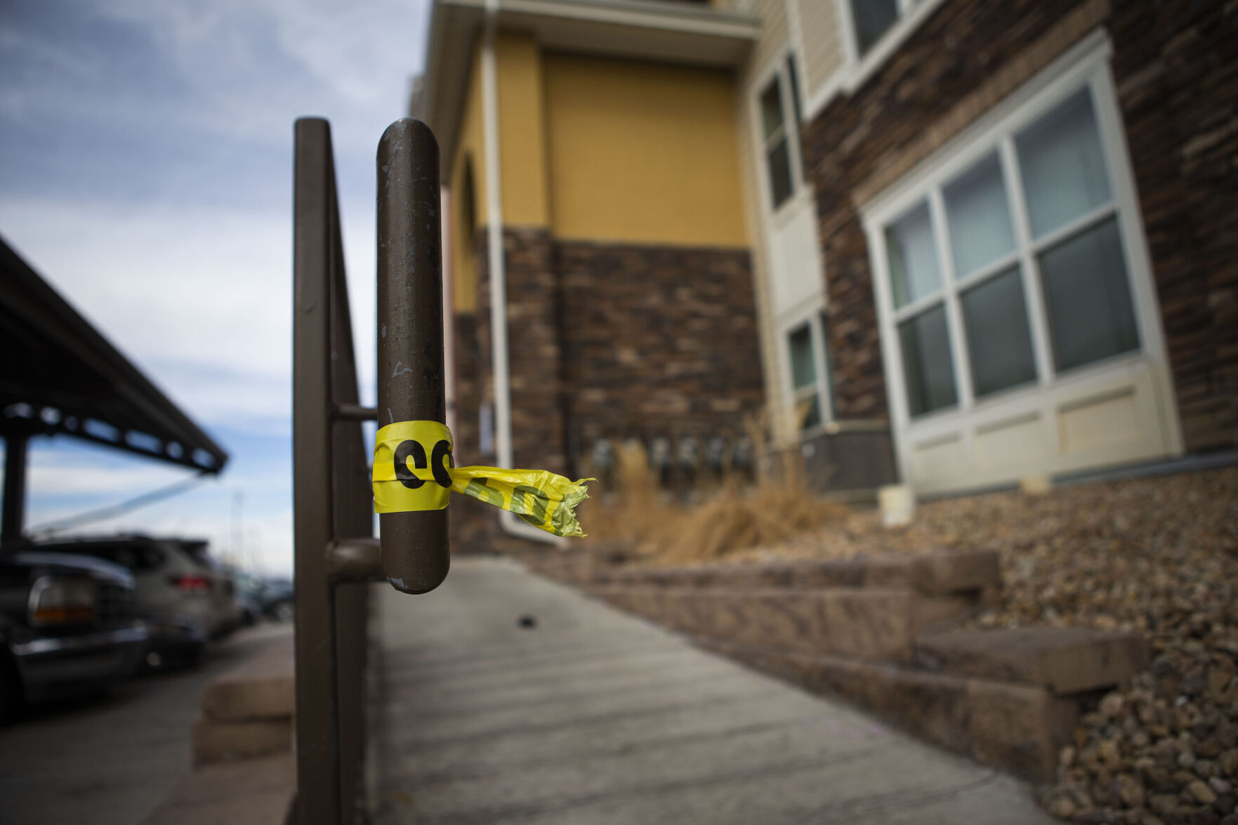 A piece of police tape is left Monday at an apartment building in Commerce City where five people were found dead Sunday night. (Timothy Hurst, The Denver Gazette)