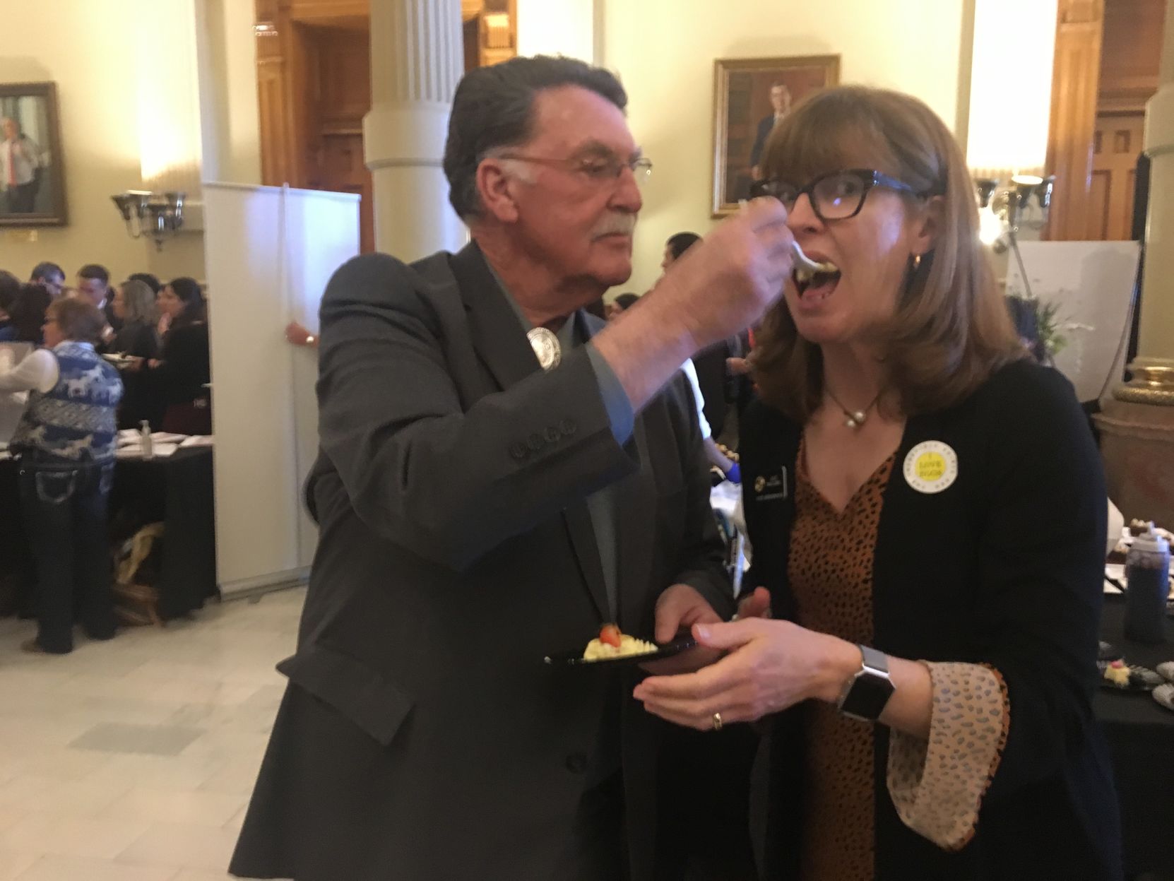 State Sen. Don Coram of Montrose feeds cheesecake to Rep. Julie McCluskie of Dillon. ((Photo by Marianne Goodland, Colorado Politics))