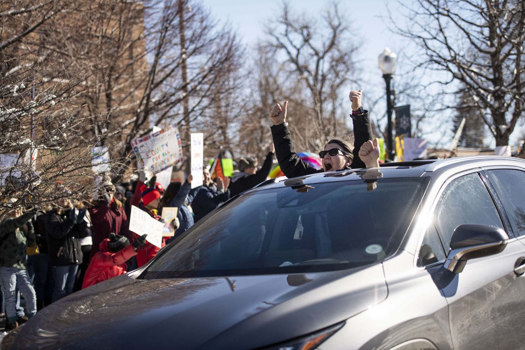 A person gives two thumbs up as they pass by hundreds of people outside the Douglas County School District headquarters in protest of the school board majority’s alleged secret meeting about forcing out superintendent Corey Wise, in Castle Rock, Colo., on Thursday, Feb. 3, 2022. The “Collaborative Action