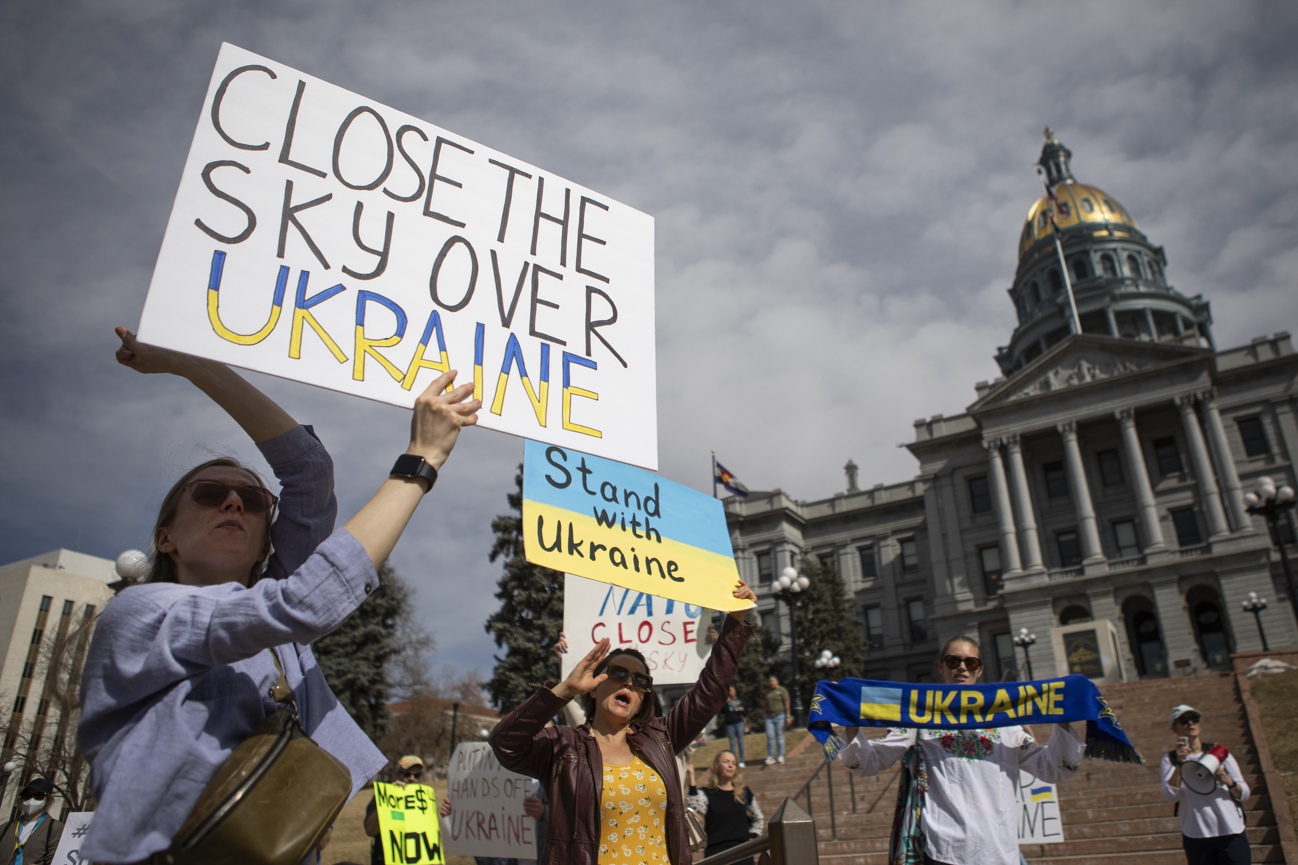 Ukrainian Oleksadra Levchenko, left, and Russian Iveria Lorenz, center, hold signs and wave to passing traffic during a protest outside the Colorado State Capitol in support of Ukraine on Wednesday, March 2, 2022, in Denver, Colo. Levchenko’s parents, grandparents and friend are in Kyiv, and her husband reportedly lost his best friend in Ukraine yesterday when his car, carrying himself, his niece and his niece’s husband, was shot by a tank and burned. The protest, organized by Nataliia Bondarchuk through Ukrainians of Colorado, is requesting that the skies over Ukraine be sheltered, help the Ukrainian military with troops, and sending ammunition and financial help to Ukraine. (Timothy Hurst/The Denver Gazette) (Timothy Hurst)