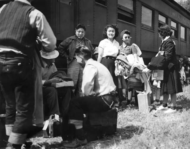Japanese-American evacuees with their belongings in front of a railway car on August 30, 1942, on the way to Camp Amache, the Granada Relocation Center, in southeastern Colorado. (U.S. War Relocation Authority photo, public domain)