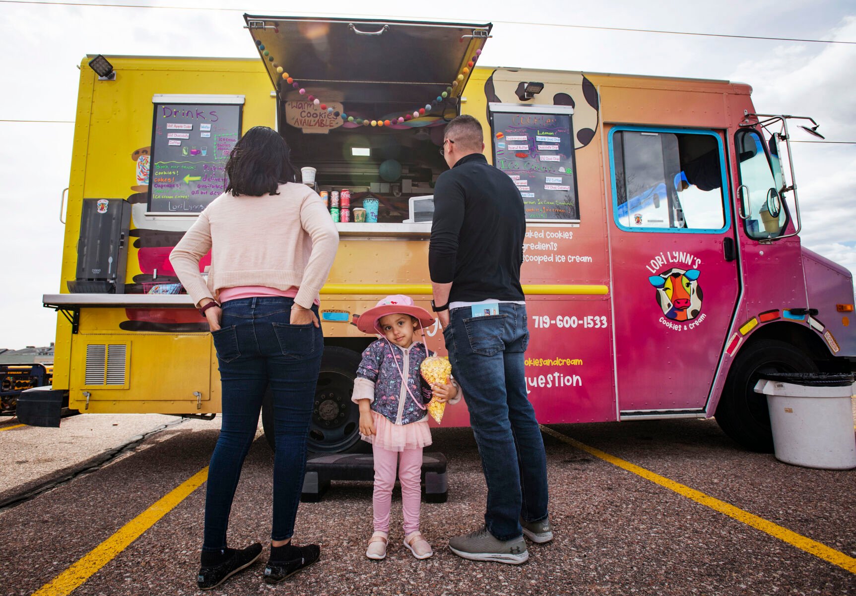 Maya, 3, waits for a sweet treat with her parents Sheeraja and James Altizer at Lori Morrissey’s food truck, Lori Lynn’s Cookies & Cream, during the 719 Food Truck Fest near Woodman Road in northeast Colorado Springs on Saturday, March 26, 2022. Morrissey features made-to-order ice cream sandwiches with her cookie made-from-scratch family recipes. (Chancey Bush/ The Gazette) (Chancey Bush/ The Gazette)