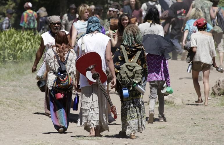 People walk along a trail at the Rainbow Family encampment of the 'non-organization's' 2014 event in Utah's Uinta National Forest. An estimated 4,000 attended that event, though some events have attracted up to 20,000 in the past. Photo Credit: Rick Bowmer, The Associated Press.
