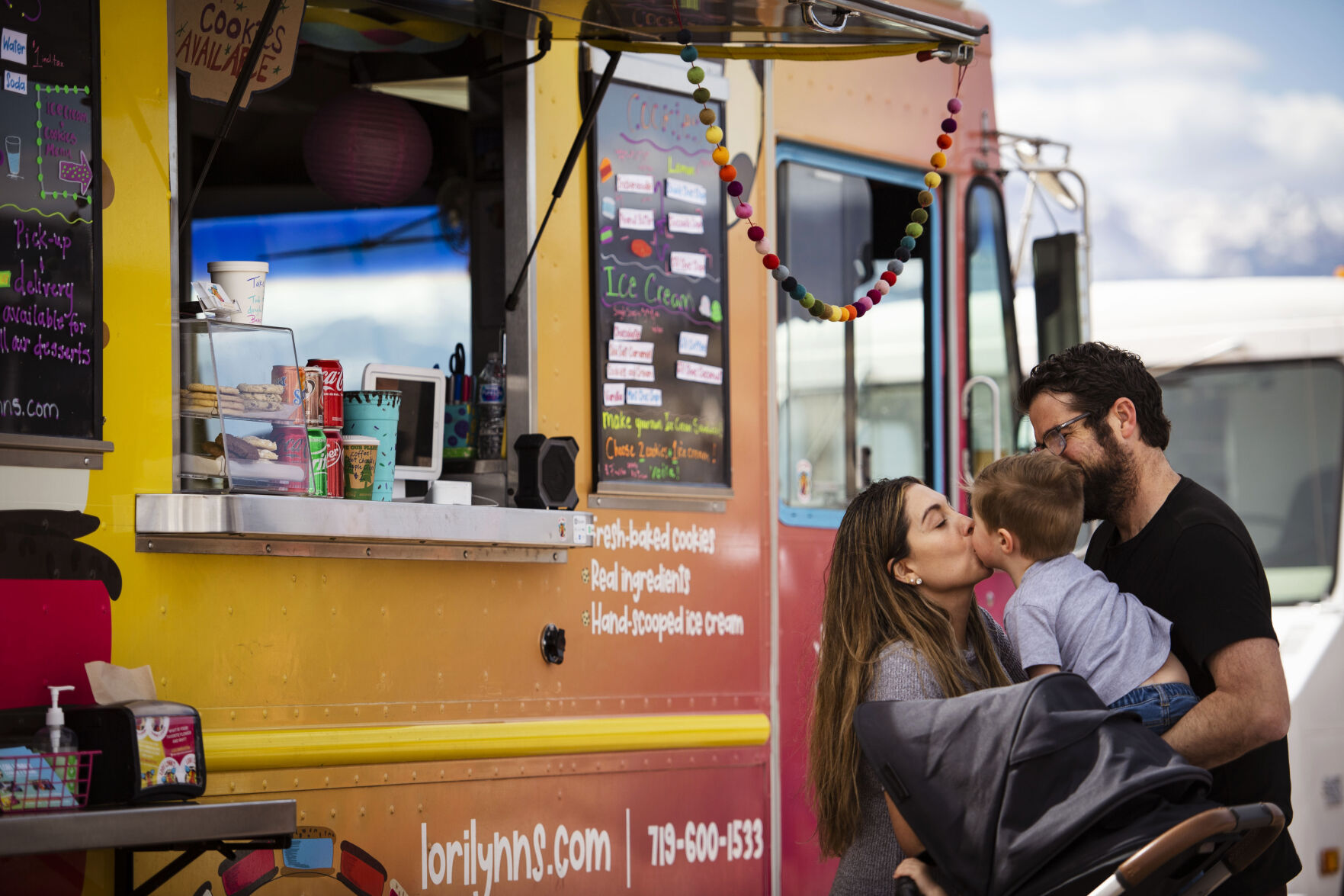 Jenny Winderbaum gives her two-year-old son Jaxson a kiss after they order sweet treats from Lori Lynn’s Cookies & Cream food truck during the 719 Food Truck Fest near Woodman Road in northeast Colorado Springs on Saturday, March 26, 2022. Morrissey features made-to-order ice cream sandwiches with her cookie made-from-scratch family recipes. (Chancey Bush/ The Gazette) (Chancey Bush/ The Gazette)