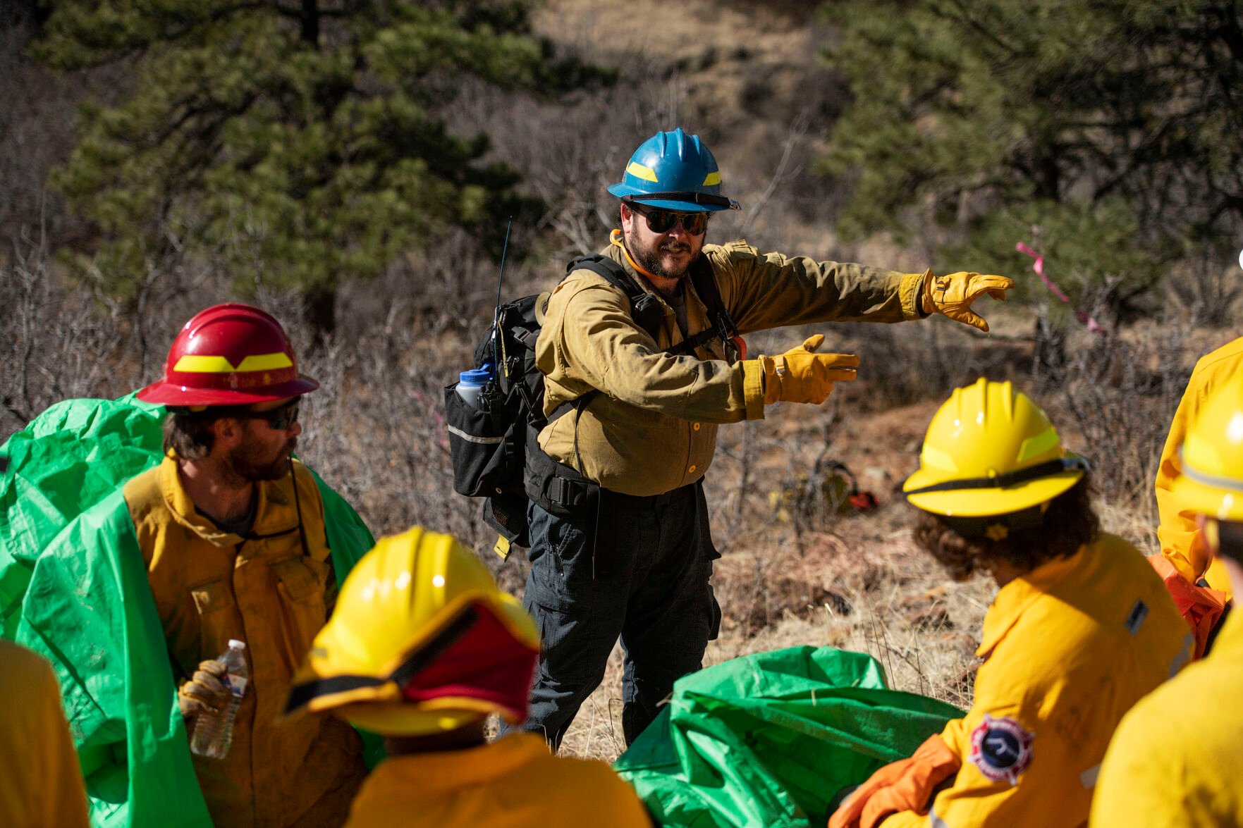 Instructor Tyler Campbell talks with students during the fire shelter deployment training durng the Colorado Wildland Fire and Incident Management Academy outdoor field day at the campus of University of Colorado at Colorado Springs on Friday, March 26, 2022. Students rotated through four stations, weather assessment, fire line digging, gridding and fire shelter deployment, as they learn of the real-life demands and techniques of containing a fast-spreading fire without water. (Chancey Bush/ The Gazette) (Chancey Bush/ The Gazette)