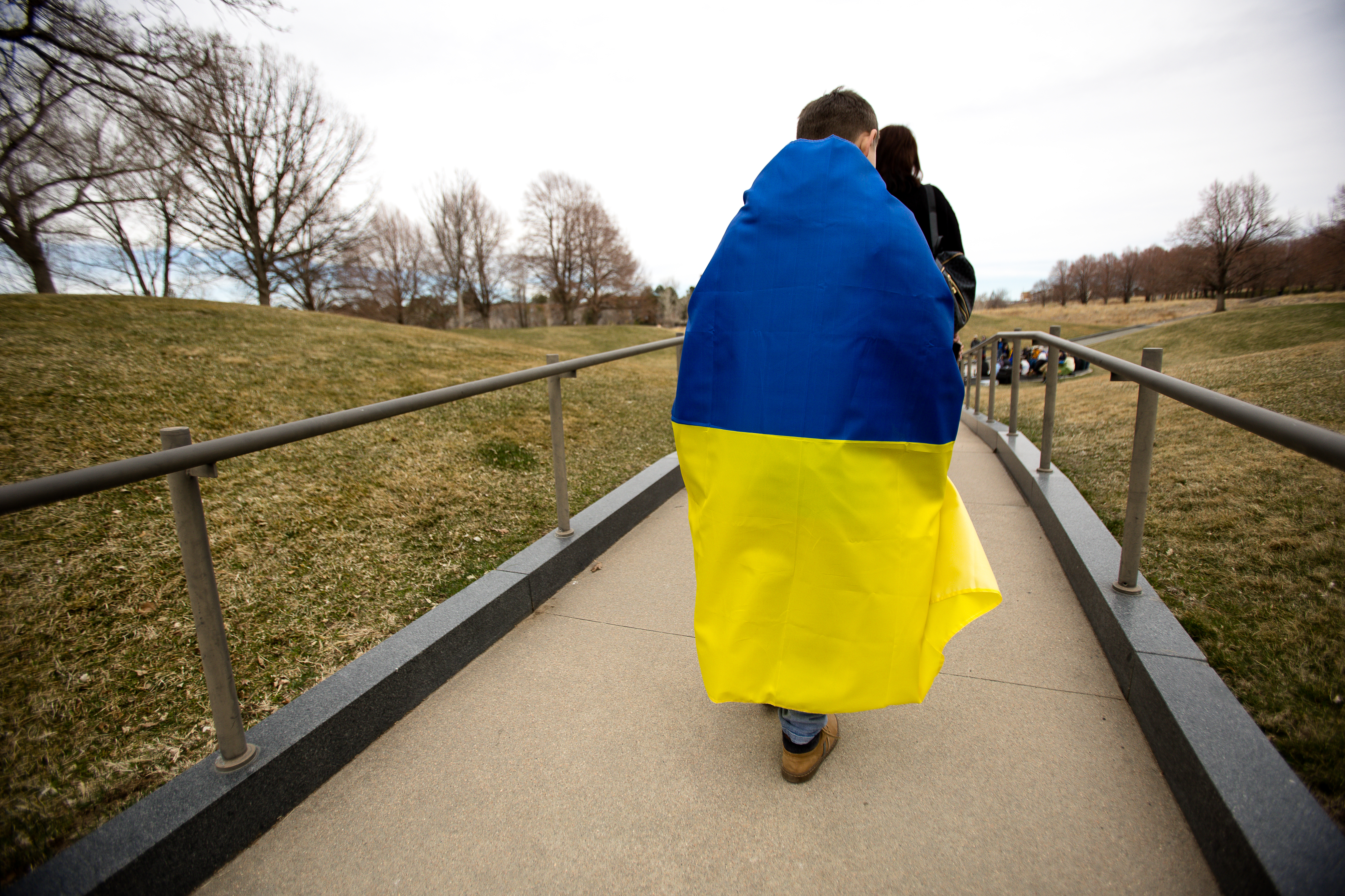 Daniel Shatalov walks to the Interfaith Gathering for Peace and in Support of the Ukrainian People event wearing the flag of his parent's home country, Sunday, March 27. ((Sara Hertwig/for The Denver Gazette))