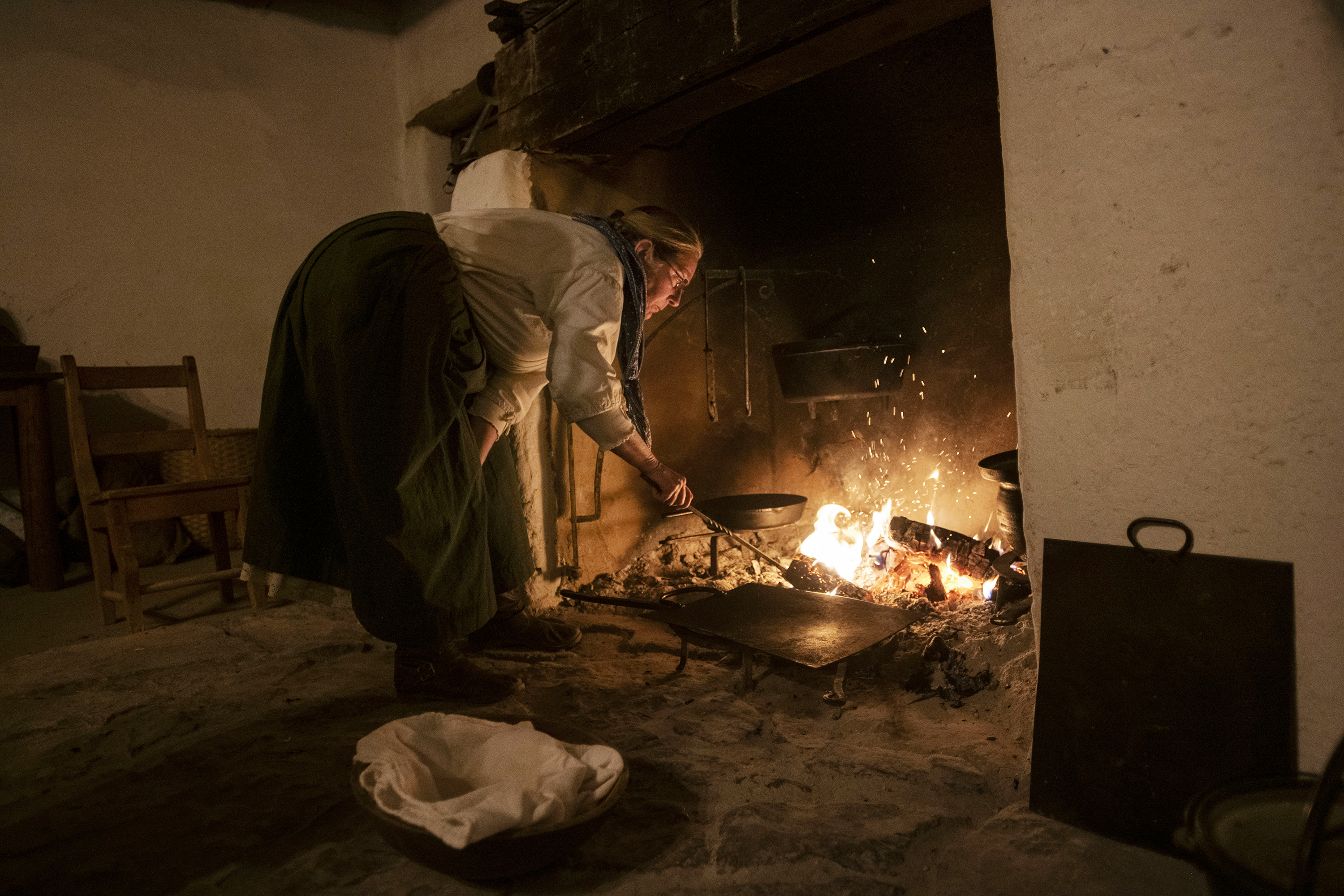 Beth Dodd, a historical interpreter portraying a Mexican labor woman, stokes the fire to prepare a meal at Bent’s Old Fort National Historic Site. (photos by Chancey Bush, The gazette)