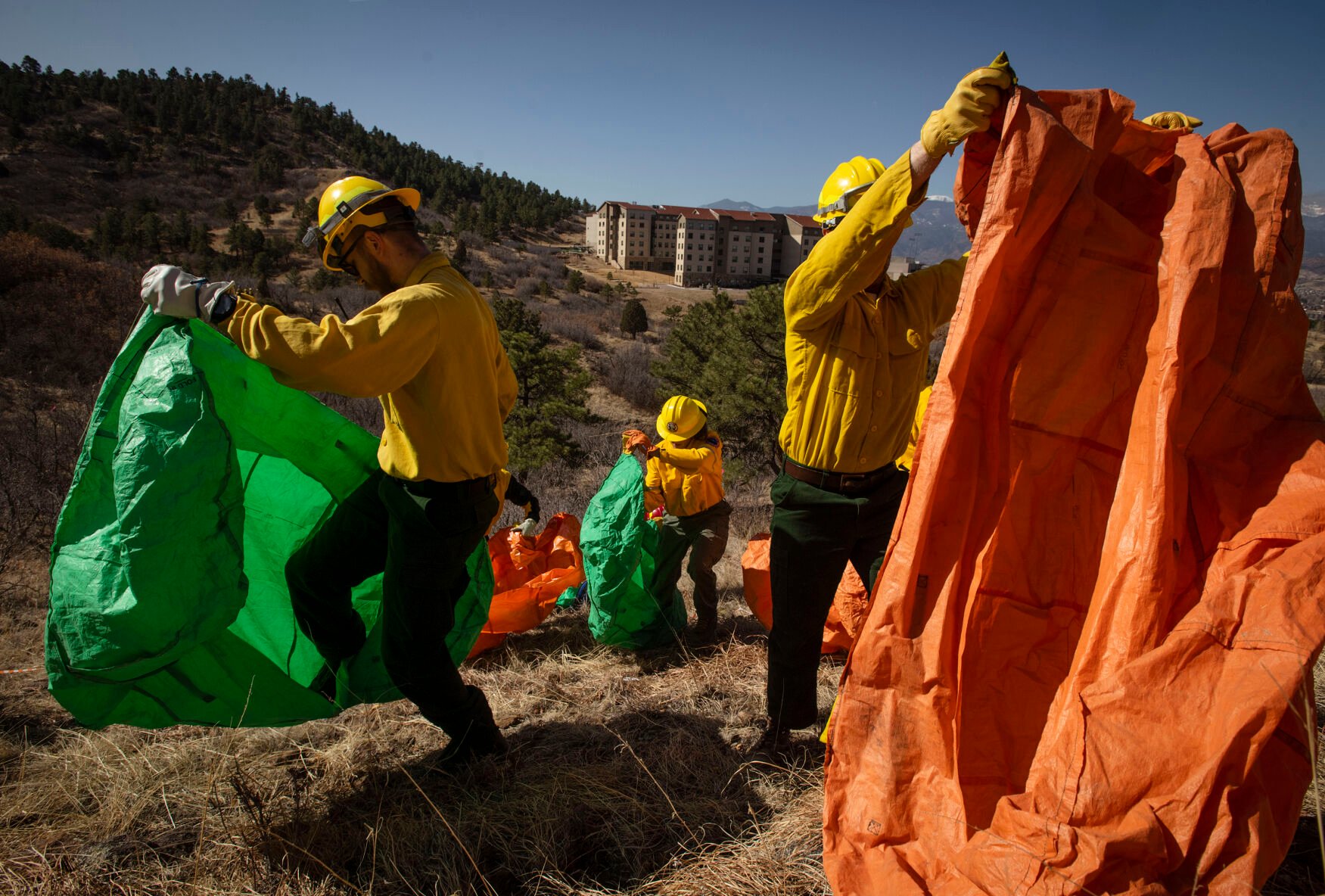 Students learn how to deploy their fire training shelters during the Colorado Wildland Fire and Incident Management Academy outdoor field day at the campus of University of Colorado at Colorado Springs on Friday, March 26, 2022. Students rotated through four stations, weather assessment, fire line digging, gridding and fire shelter deployment, as they learn of the real-life demands and techniques of containing a fast-spreading fire without water. (Chancey Bush/ The Gazette) (Chancey Bush/ The Gazette)