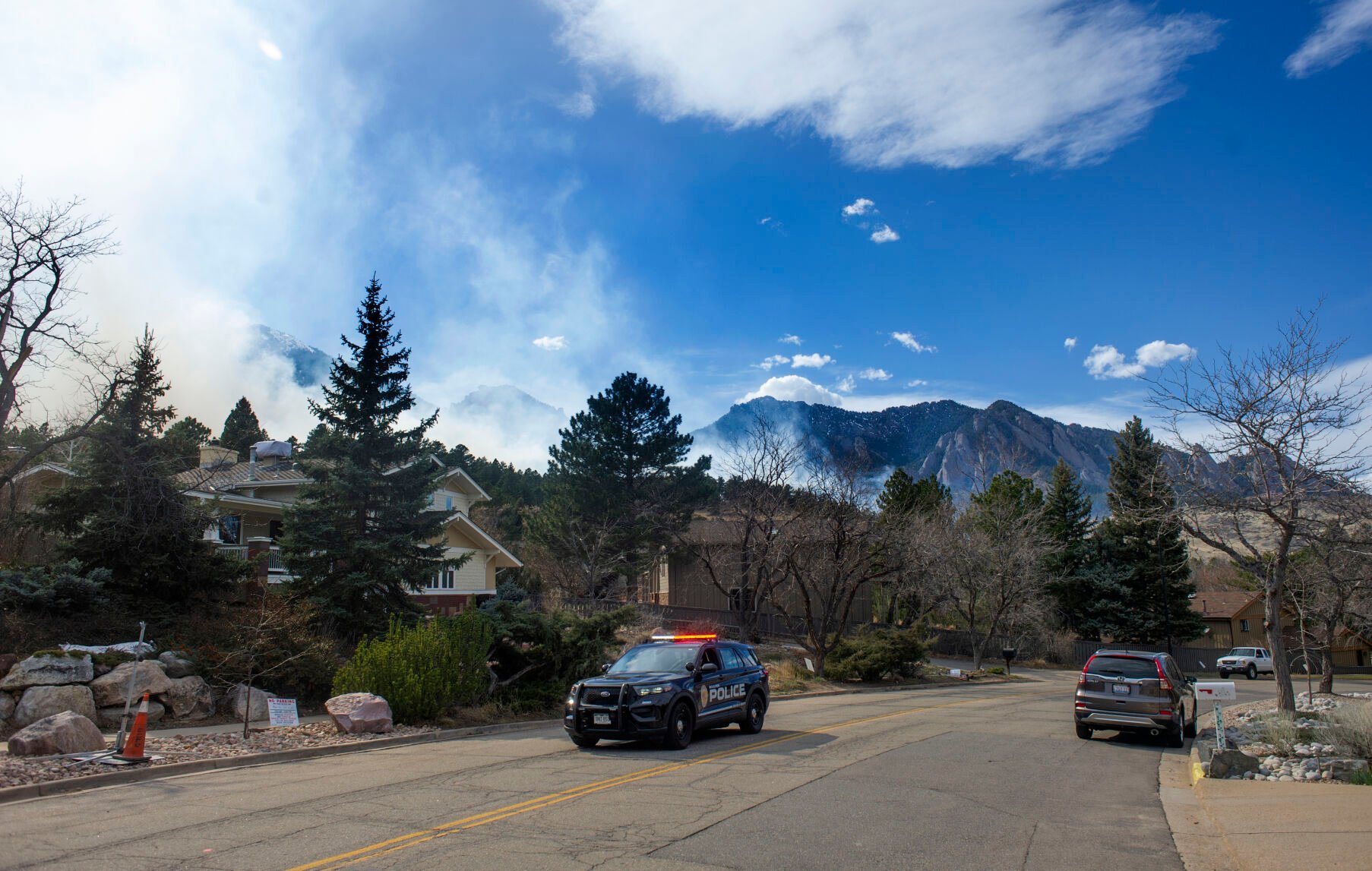 A police vehicle drives through an evacuation zone in south Boulder as smoke from the NCAR Fire obscures Bear Peak, on March 26, 2022, in Boulder, Colo. (Jacob Byk/For The Denver Gazette)