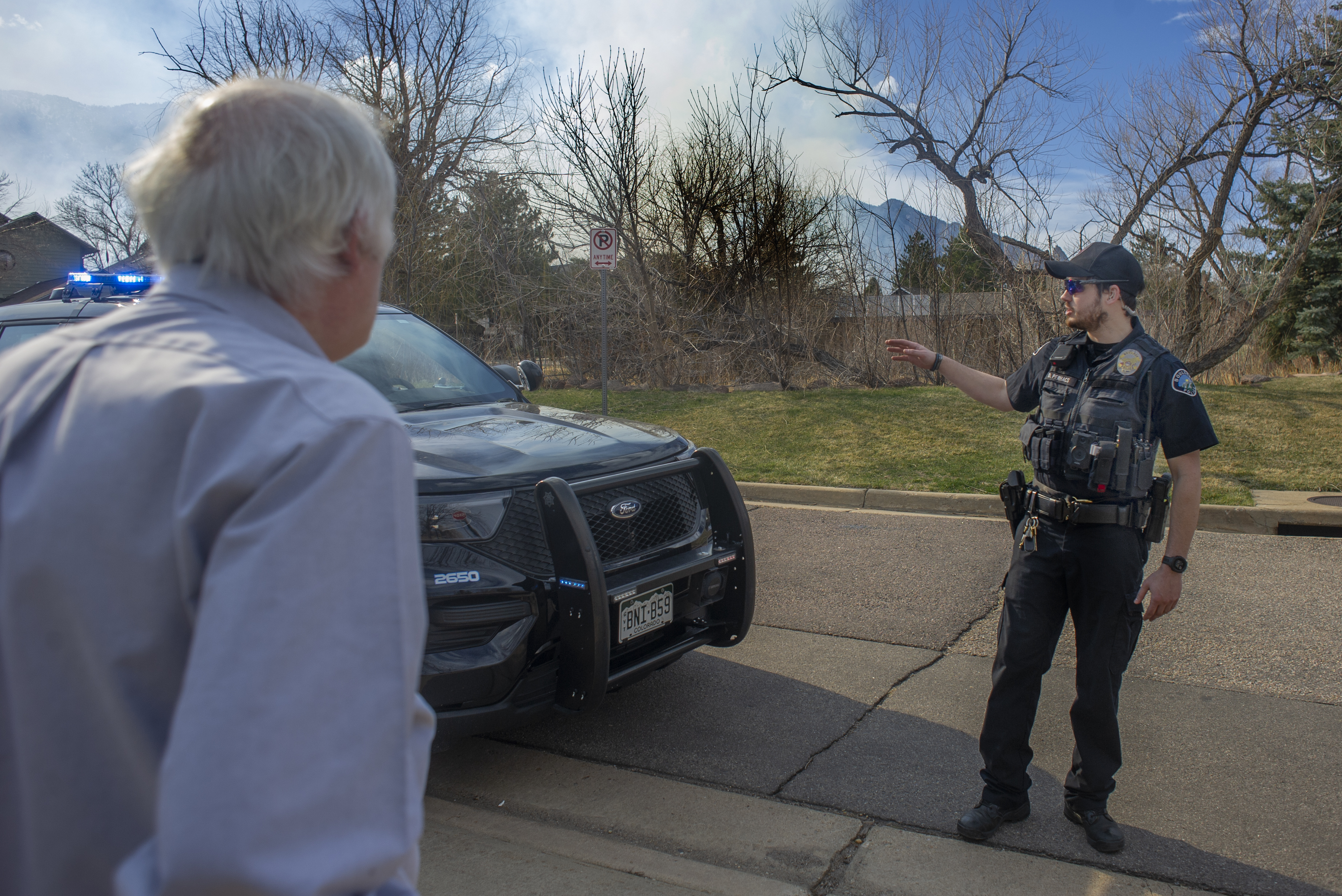 Boulder Police Officer D. Perhacs speaks with Tony Lefton, a resident since 1986, about evacuating quickly as smoke billows above from the NCAR Fire on March 26, 2022, in Boulder, Colo. (Jacob Byk/For The Denver Gazette)