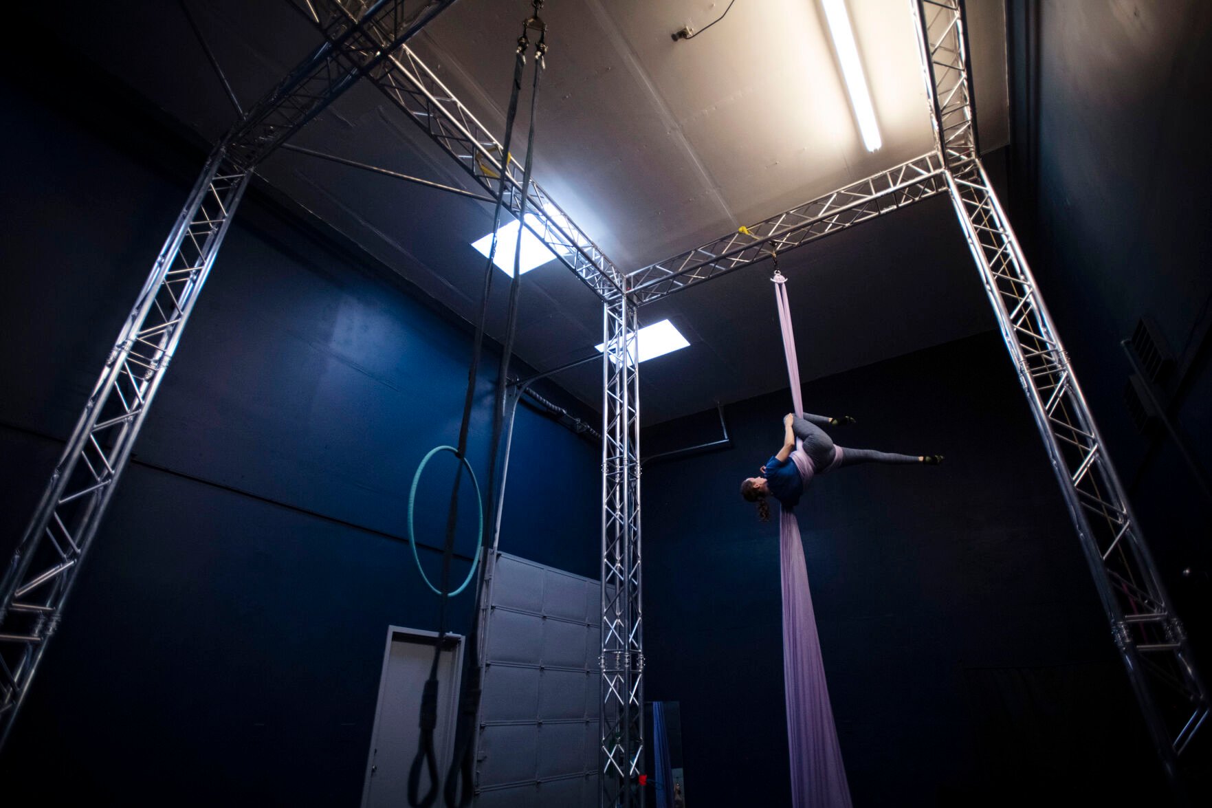 LEFT: Olivia McCommons, 27, is suspended in the air by an aerial silk at Urban Cirque studio in Colorado Springs on Tuesday, March 15, 2022. Owner Katrina Diaz opened her studio in January, where she shares her passion of circus-style fitness with teens and adults, teaching the art of silks, hoops and aerial fitness ranging from beginner to intermediate classes. (Chancey Bush/ The Gazette)