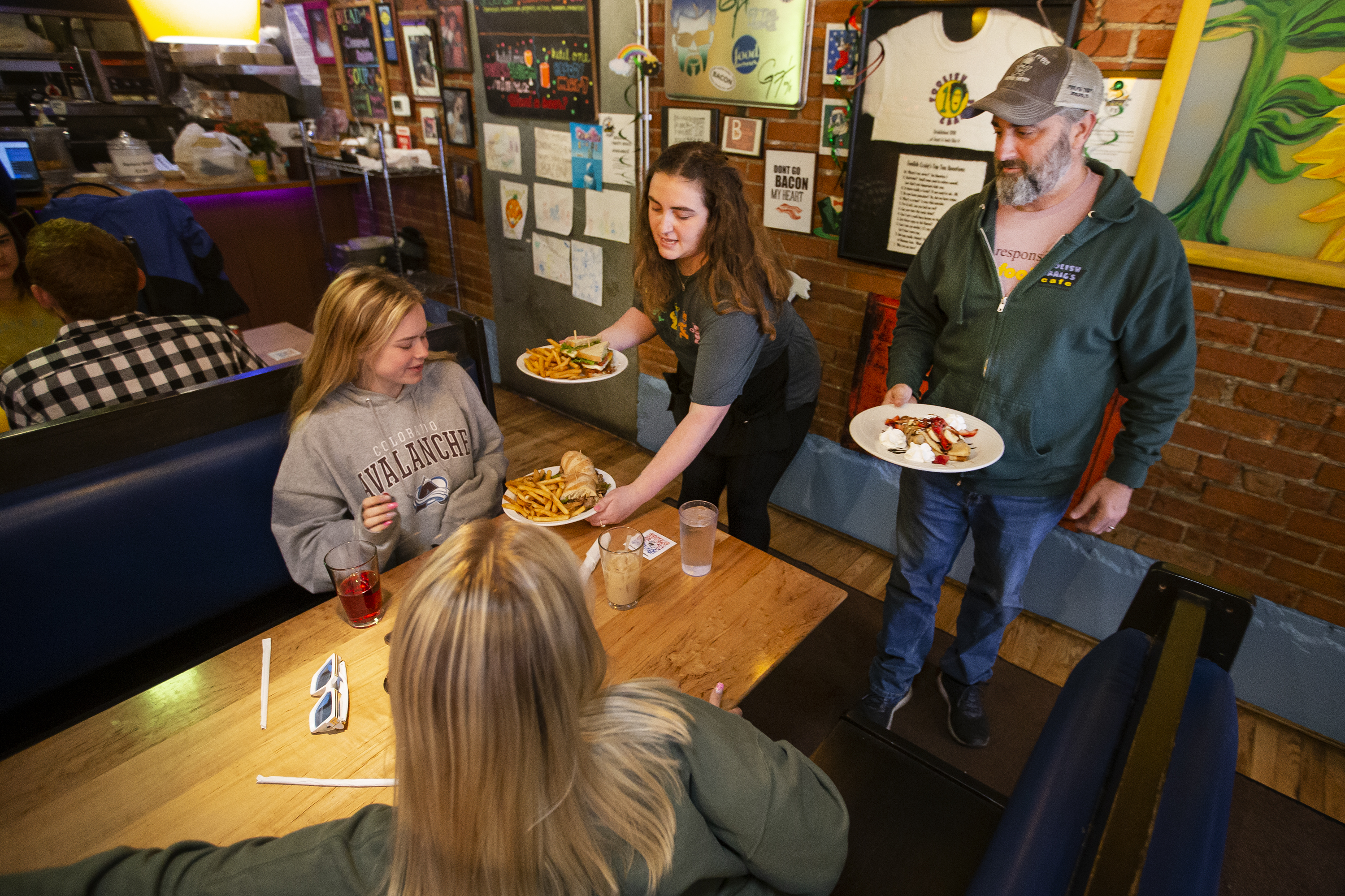 Server Lucy Isles and co-owner Craig Moelis deliver an order of the Philly steak sandwich, the BLT guacamole and the hot strawberry & Nutella crêpe to customers Annie Dyson and Lulu Shiesley at Foolish Craig’s Cafe. (Timothy Hurst)