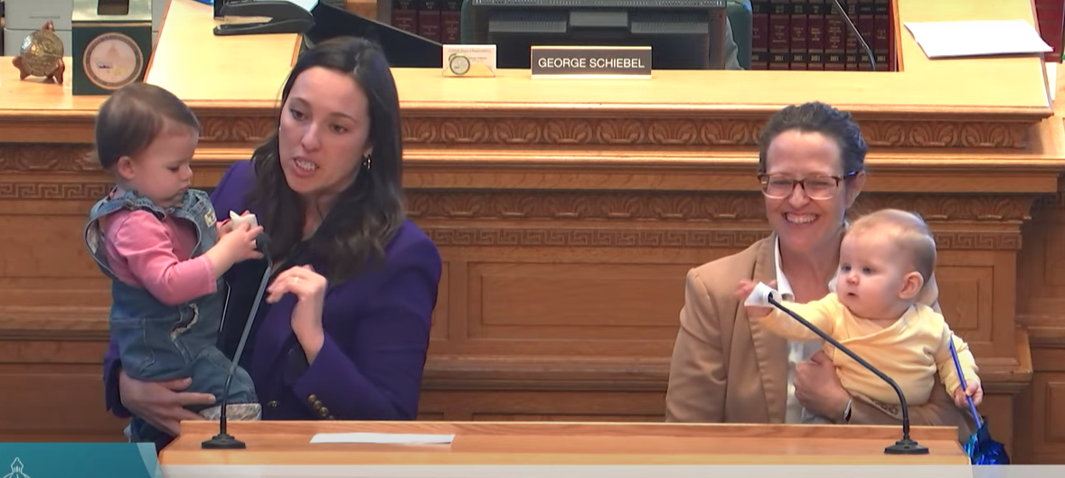 Rep. Kerry Tipper (at left, with daughter Evan) and House Majority Leader Rep. Daneya Esgar (with daughter Marlo) during final passage of House Bill 22-1153. Courtesy Colorado Channel. Both daughters had fun playing with the microphones in the well of the House.