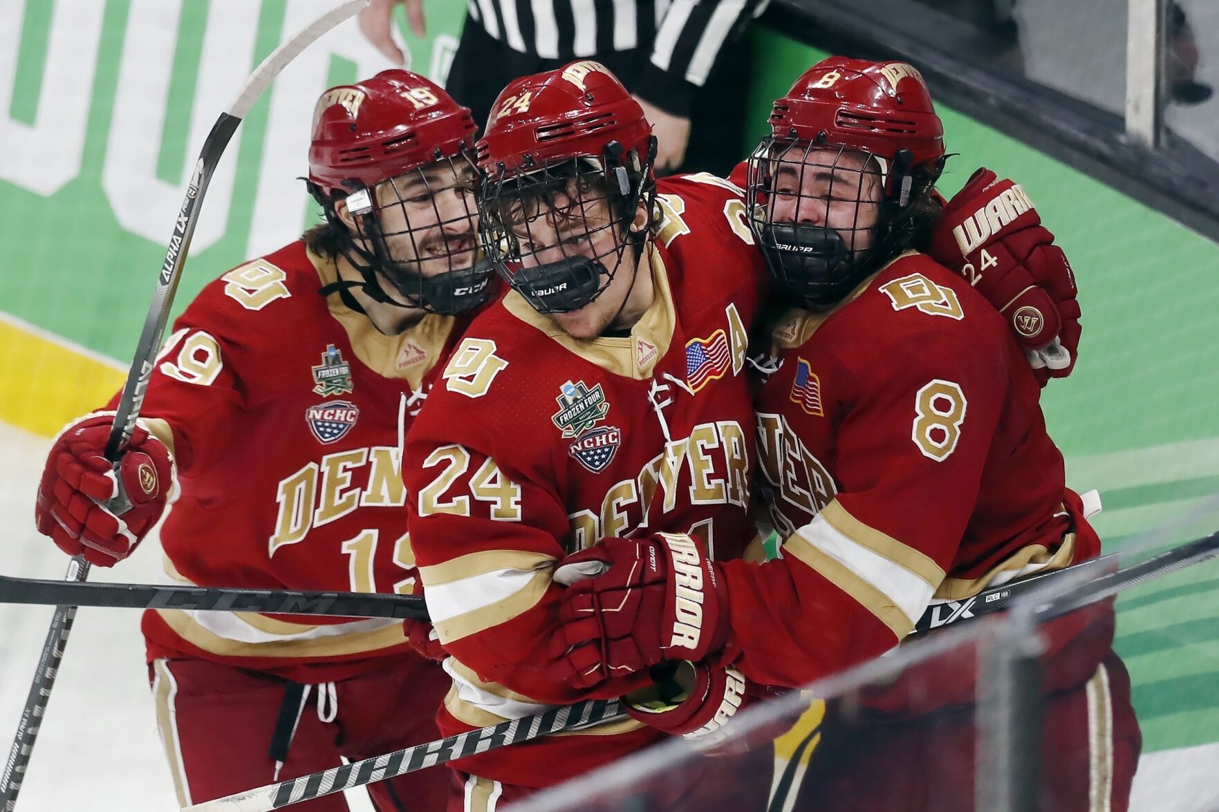 Denver’s Carter Savoie, right, celebrates his winning goal with Bobby Brink, middle, and Cole Guttman in overtime Thursday during a Frozen Four semifinal game against Michigan in Boston.