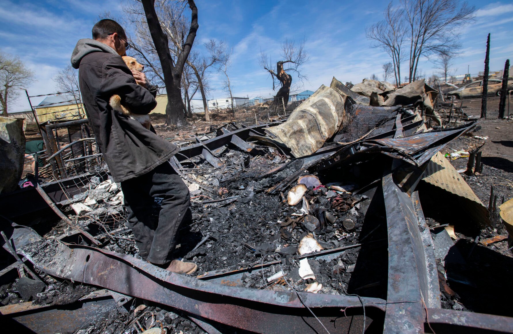 Savino Sanchez holds his mother-in-law’s dog as he and his family search through the remains of their home in Monte Vista Friday after a fire fueled by high winds Wednesday burned 17 structures and displaced six families. (Christian Murdock, The Gazette)